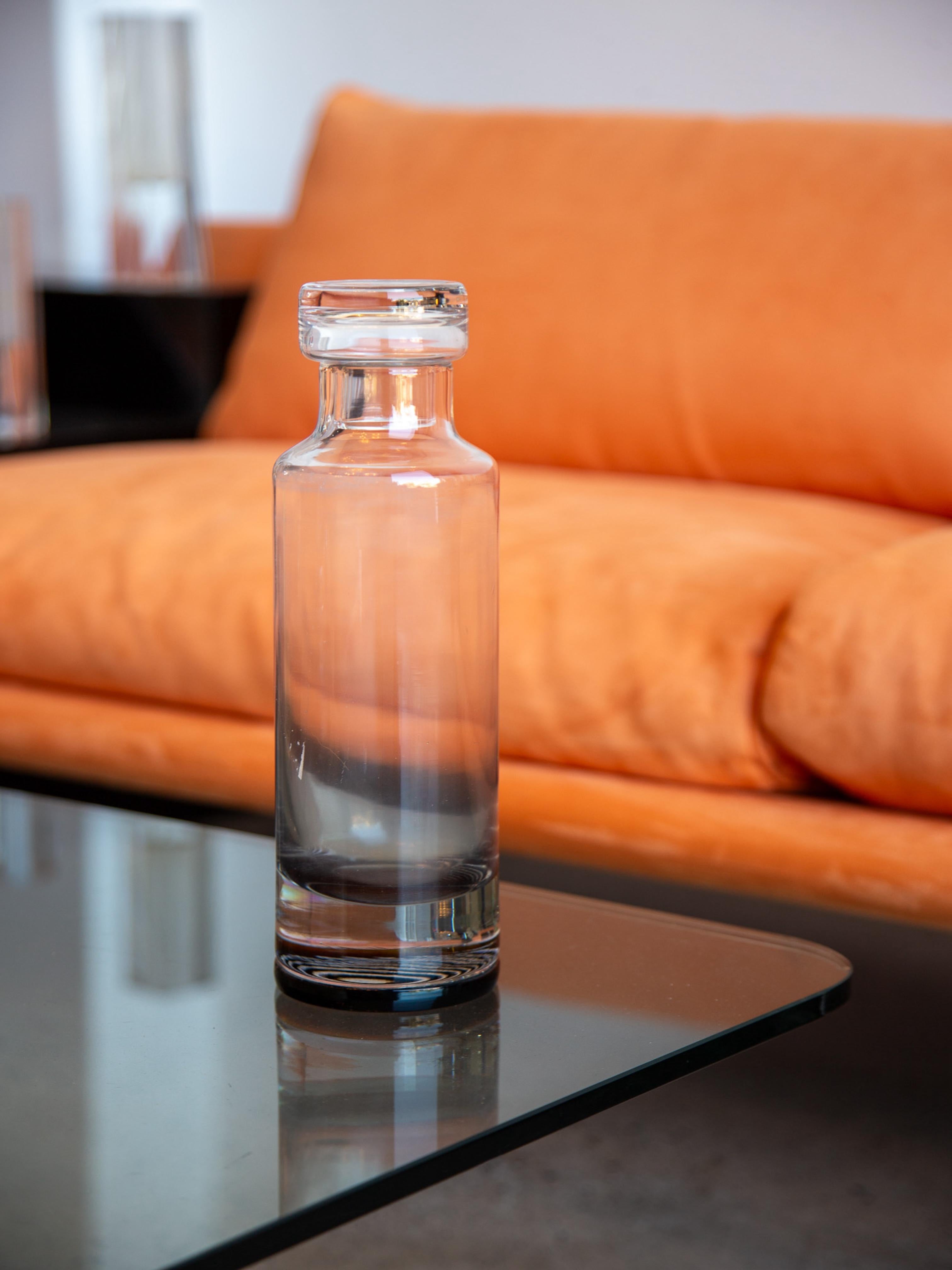 Progettato con una forma pulita e moderna, questo decanter scultoreo in vetro si integra perfettamente in ambienti di metà secolo e contemporanei. Il tappo originale di Murano ne accresce il valore collezionistico e offre anche un uso pratico per