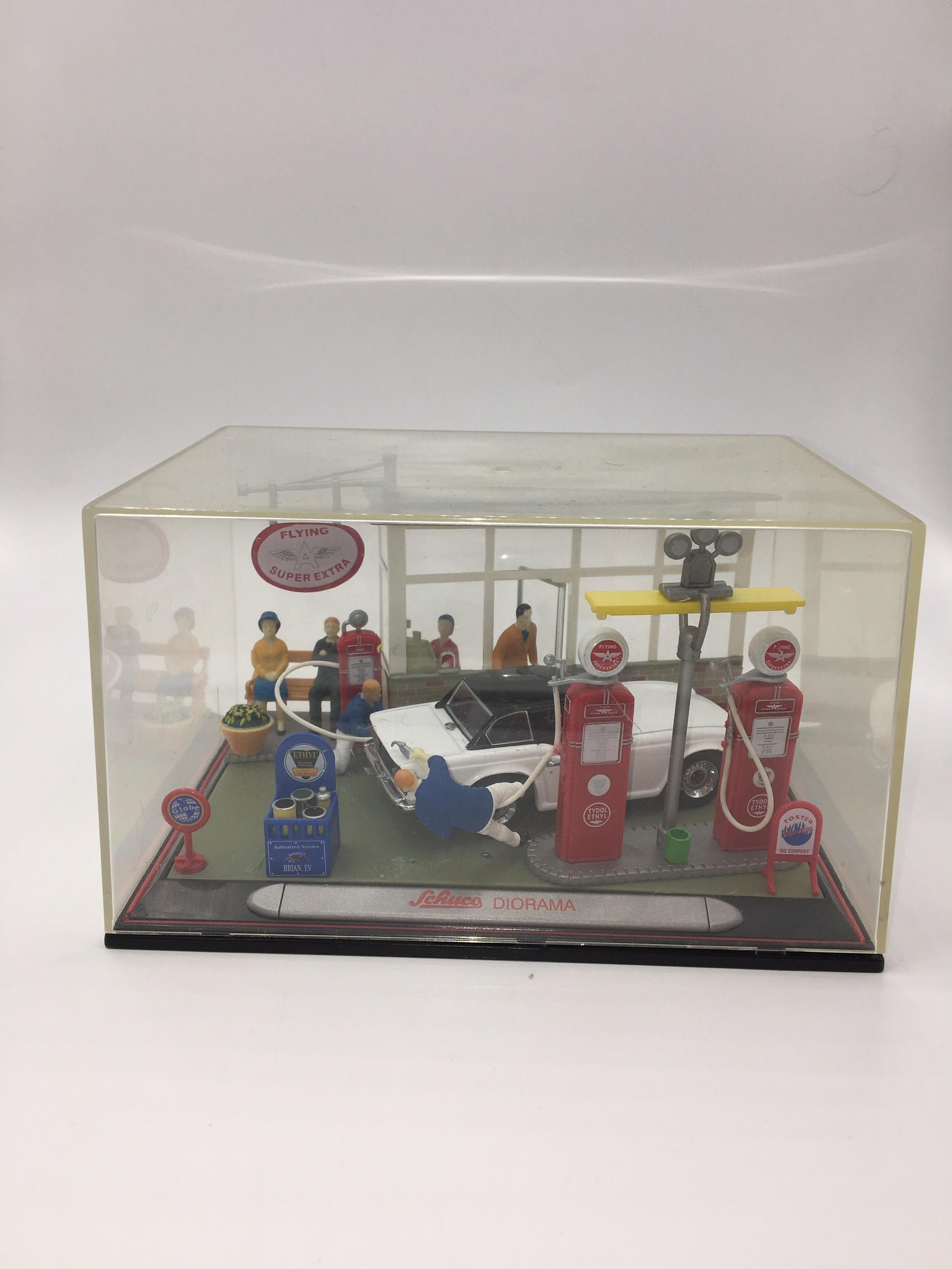 Beautiful diorama that represents a petrol station, where 2 mechanics are serving a MG B, while the occupants wait seated. Another client comes out of the station and a cashier is in charge of charging the services provided by the two operators. A