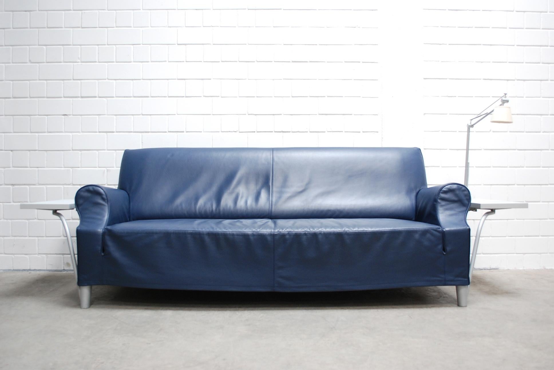 Philippe Starck a conçu ce modèle de canapé-lit.
Canapé en cuir bleu comprenant une lampe Flos Archimoon. La lampe est amovible.
Il y a des étagères à côté de chaque accoudoir.
Pieds en aluminium.
