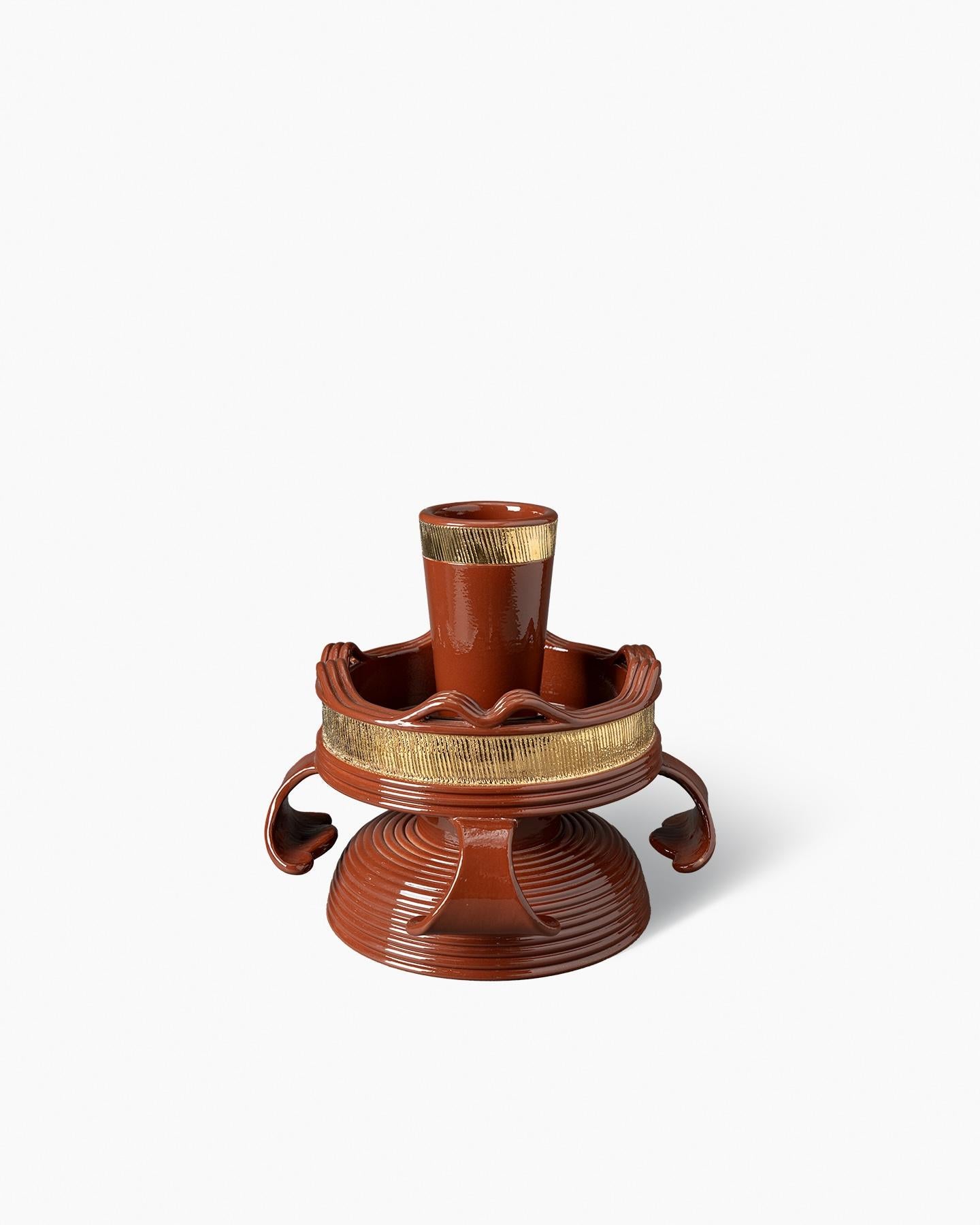 PMA–2
Centrotavola
cm. 27,5H x 28Ø
Marrone lucido

At once a fruit bowl and a vase, this piece features floral handles that pay tribute to some of the works preserved in the Bitossi Historical Archive, as does the stepped golden band that decorates