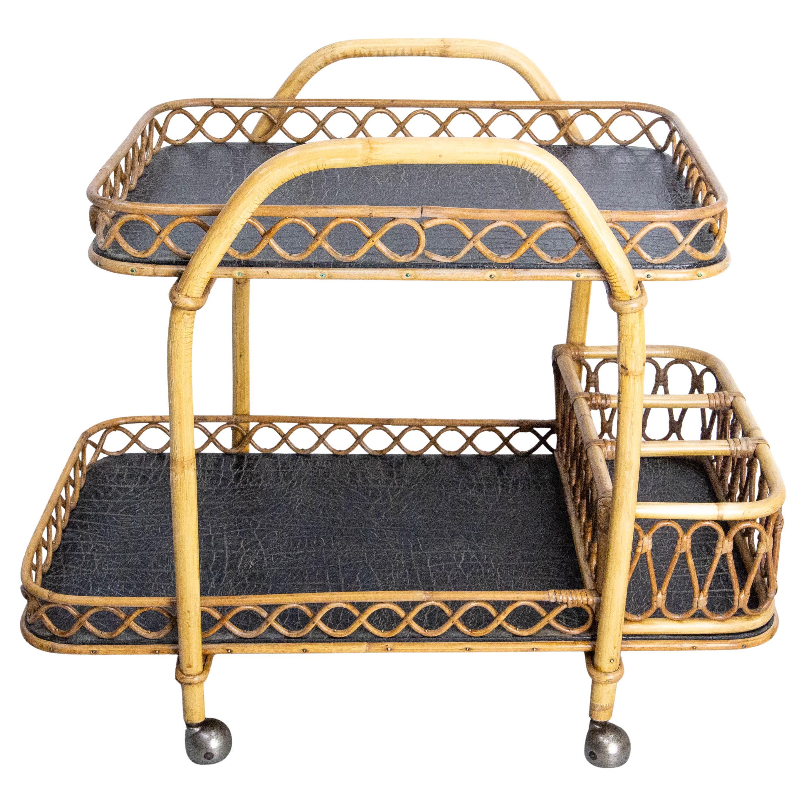 Rattan and black skai serving trolley bar cart drinks midcentury, made circa 1950.
This serving trolley can also be used as a side table.
In good working order.
Good vintage condition.

Measures of the tray:  24.02 x 16.54 in. (61 x 42