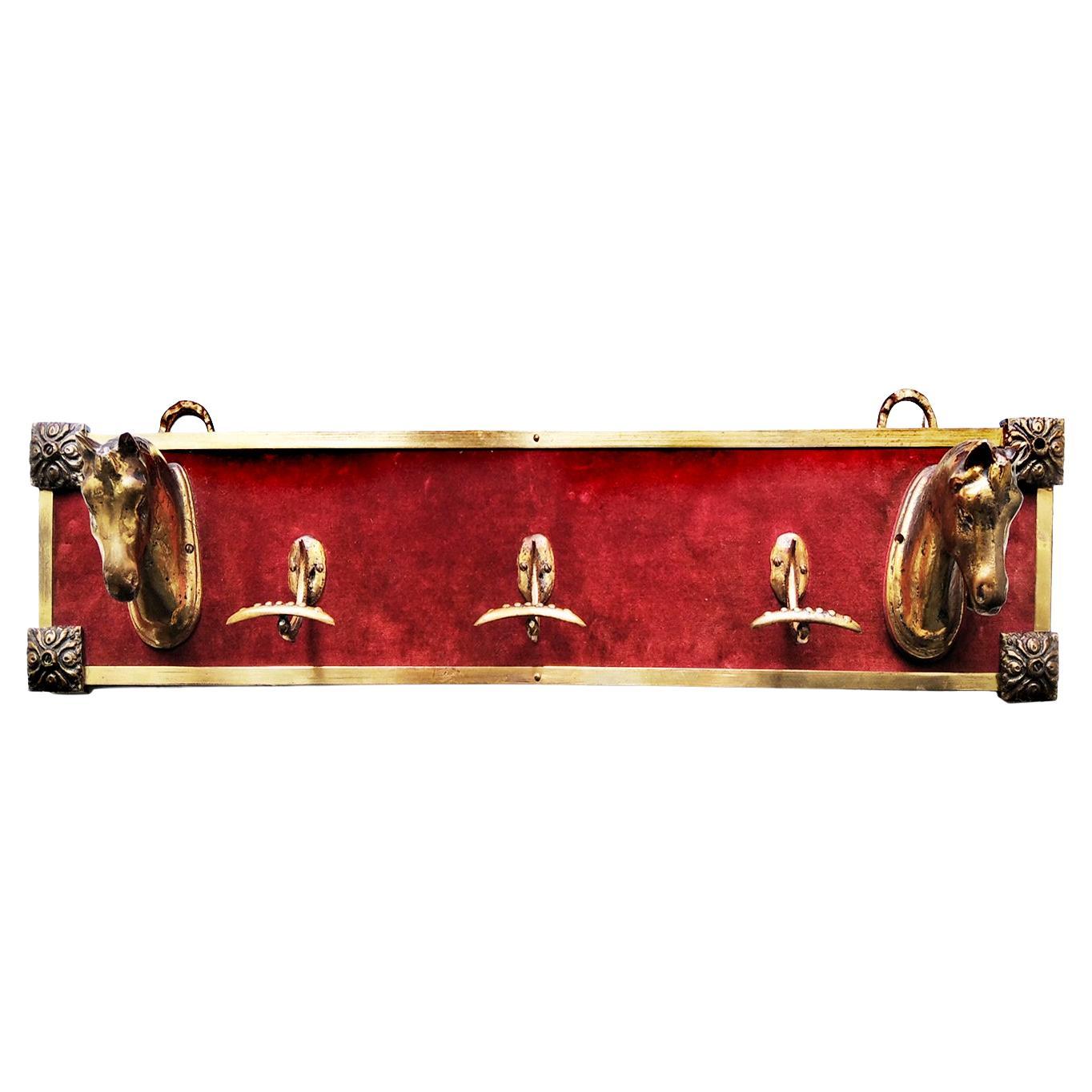 Wall coat rack in brass and velvet
It is a high quality piece

Beautiful wall coat rack with 5 hangers, two of them with a precious horse head sculpture in solid bronze on a red / maroon velvet mantle framed

 It is a coat rack of good quality and