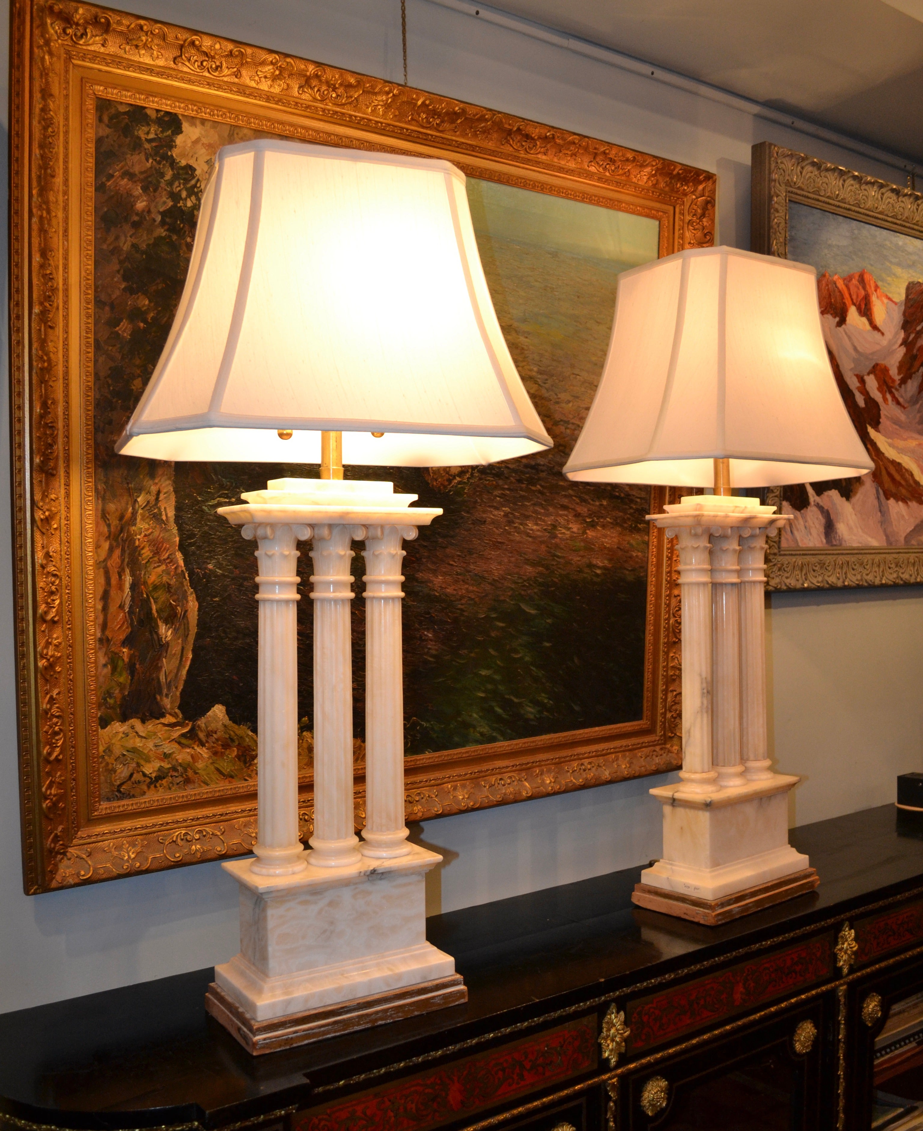 A pair of carved alabaster lamps representing ancient ‘Roman’ architecture; each having three tall fluted columns with Corinthian capitals supporting a stepped top and resting on a rectangular stepped base on a further wooden base.
 