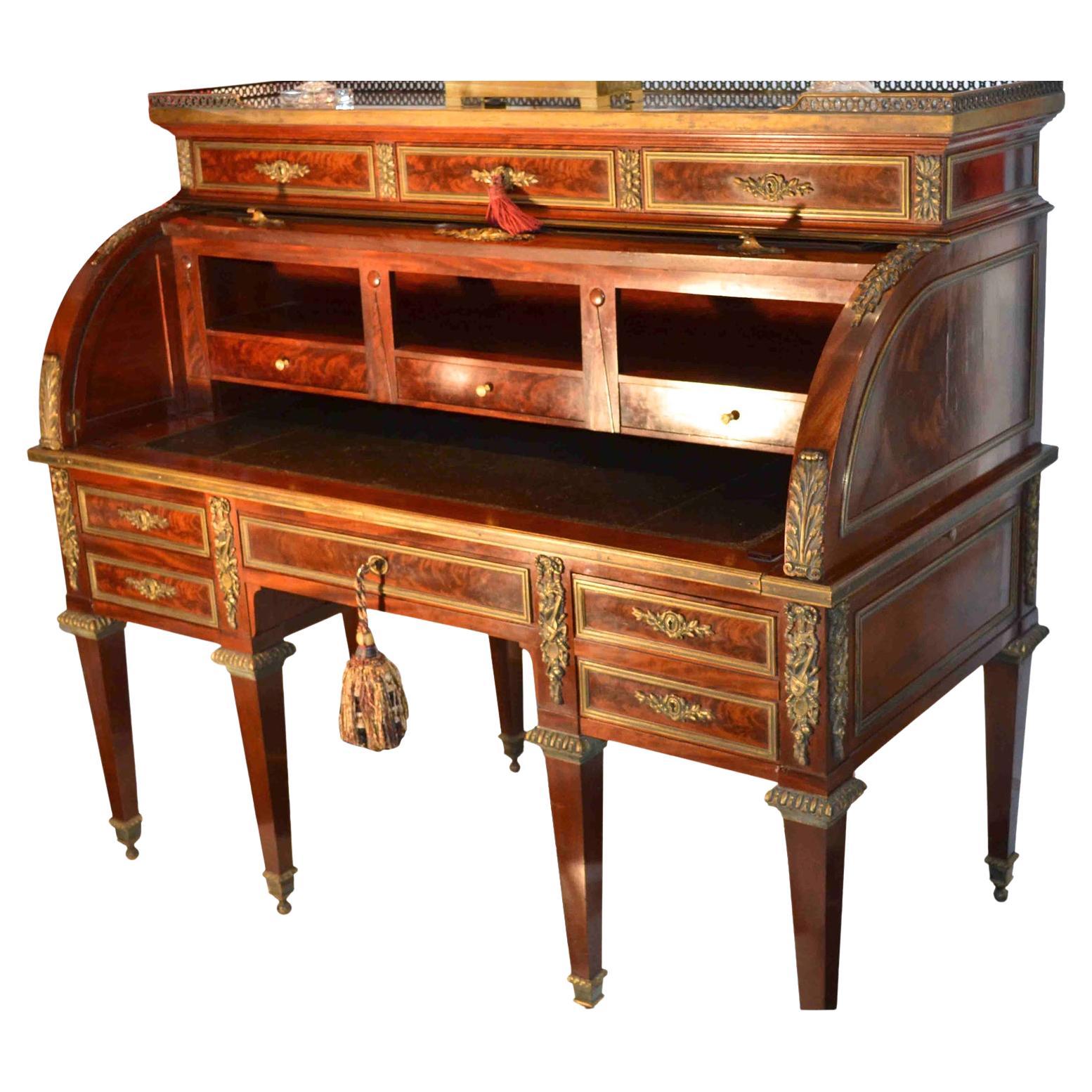Un'imponente scrivania con piano a rotelle in stile Luigi XVI, in mogano splendidamente scolpito e con montature in bronzo dorato; il piano in marmo verde con una galleria in bronzo sopra tre lunghi cassetti, il piano a rotelle aperto rivela una
