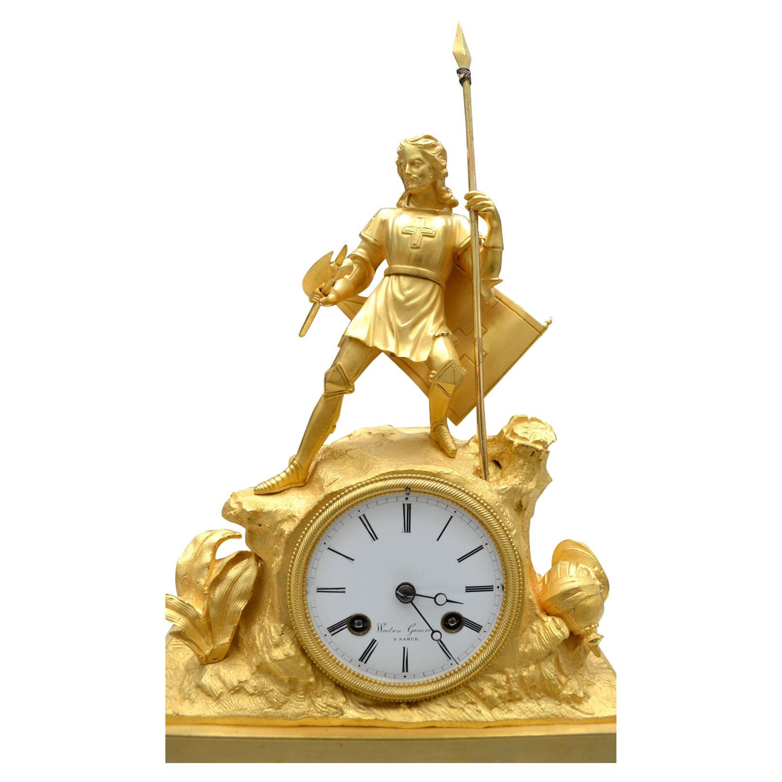 A finely cast gilt bronze figurative clock showing knight crusader stranding on rocky terrain after battle. The knight has a spear in one hand, a battle axe in the other, his helmet lying on the ground at his feet and his shield slung back across
