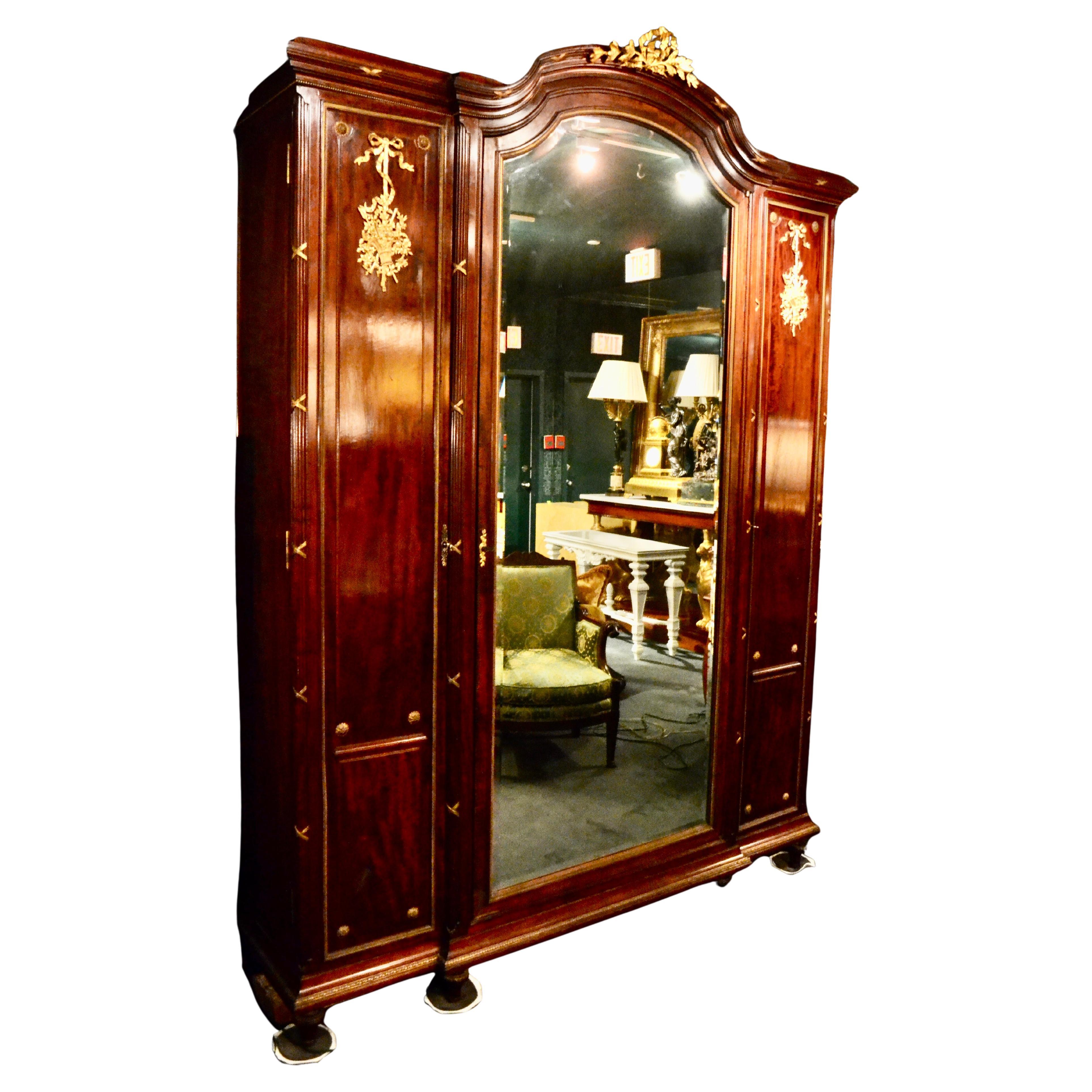 Un magnifico esemplare di inizio Novecento francese  Armoire in stile Luigi XVI in mogano e bronzo dorato alla maniera di Francois Link.  La parte superiore ad arco è centrata da una corona d'alloro in bronzo dorato che sovrasta una grande porta