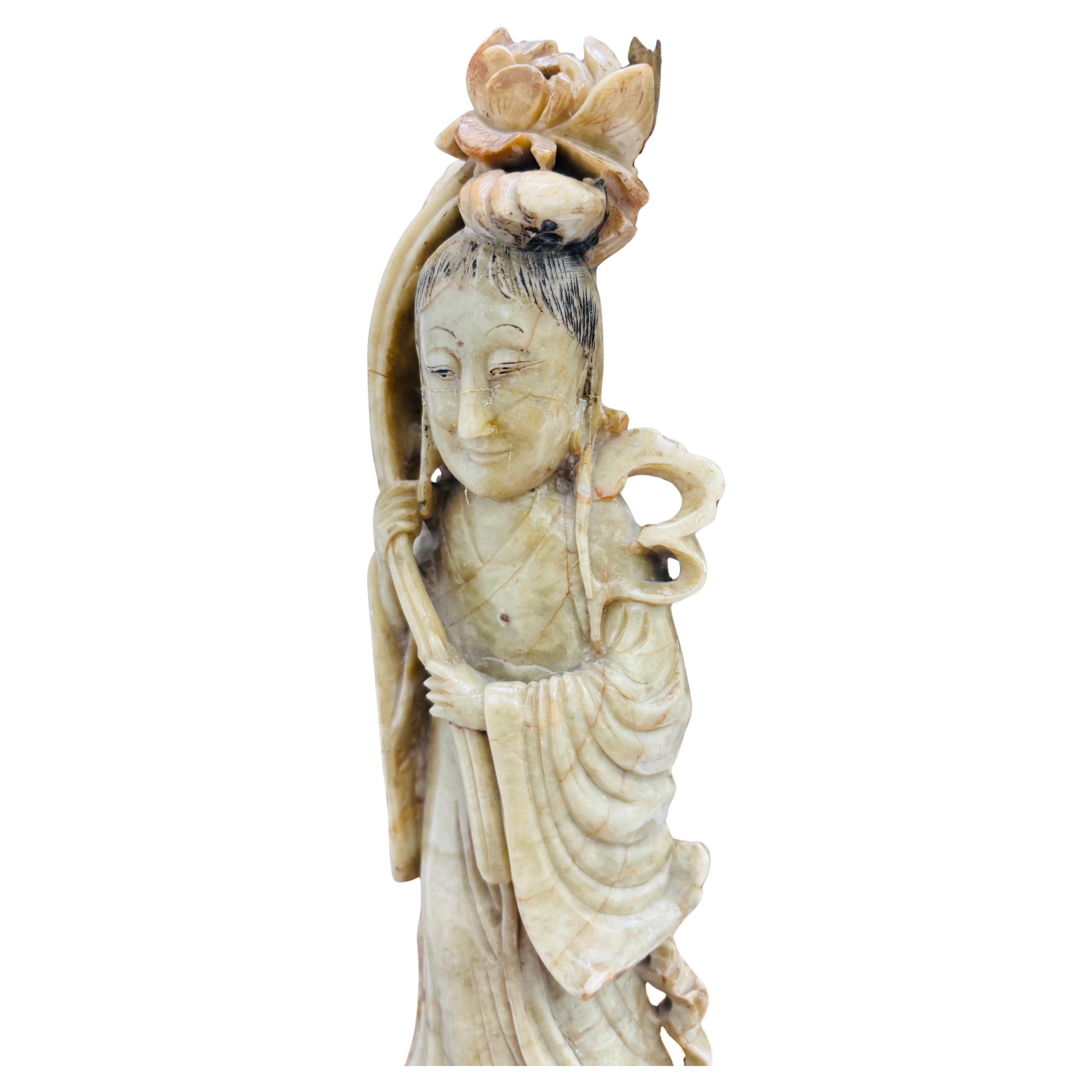 An early 20th century unusual two tone carved soapstone lamp  featuring a  cream colored standing goddess Guanyin set on a brown pedestal the whole presently mounted on a  round bronzed metal base.