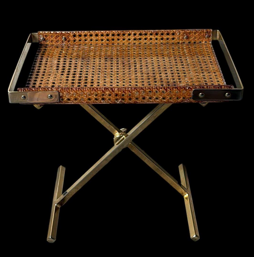 Élégante table pliante italienne, dotée d'une base en X en laiton poli, surmontée d'un plateau amovible raffiné en lucite transparente, renfermant un insert tressé à la main en paille de Vienne véritable. Le design à la fois léger et sophistiqué