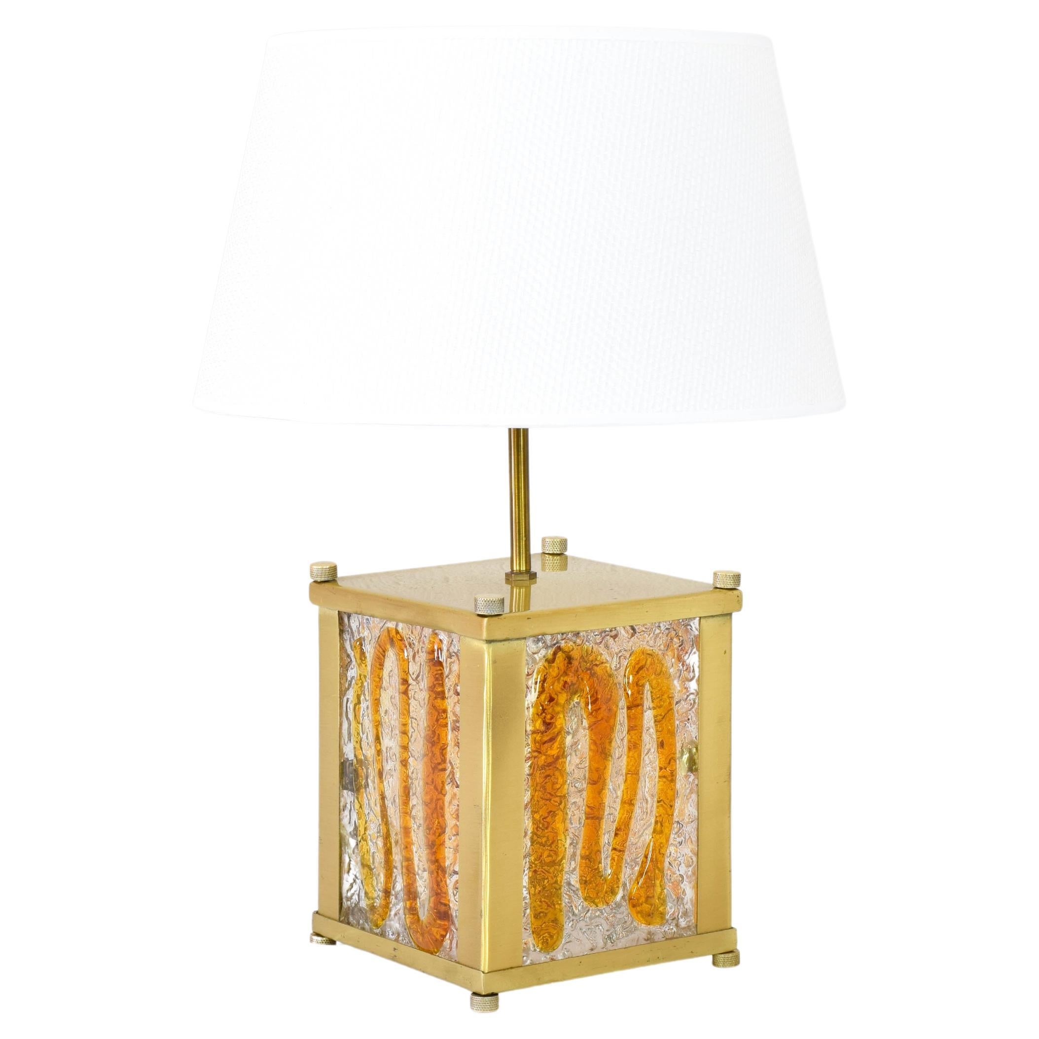 Antique Italian table lamp in the manner of Toni Zuccheri.
The lamp is made up of a cubic brass-plated metal body, amber-colored Murano glass plates and a lampshade.
The lamp has two lamp holders, one that illuminates the lampshade and the other