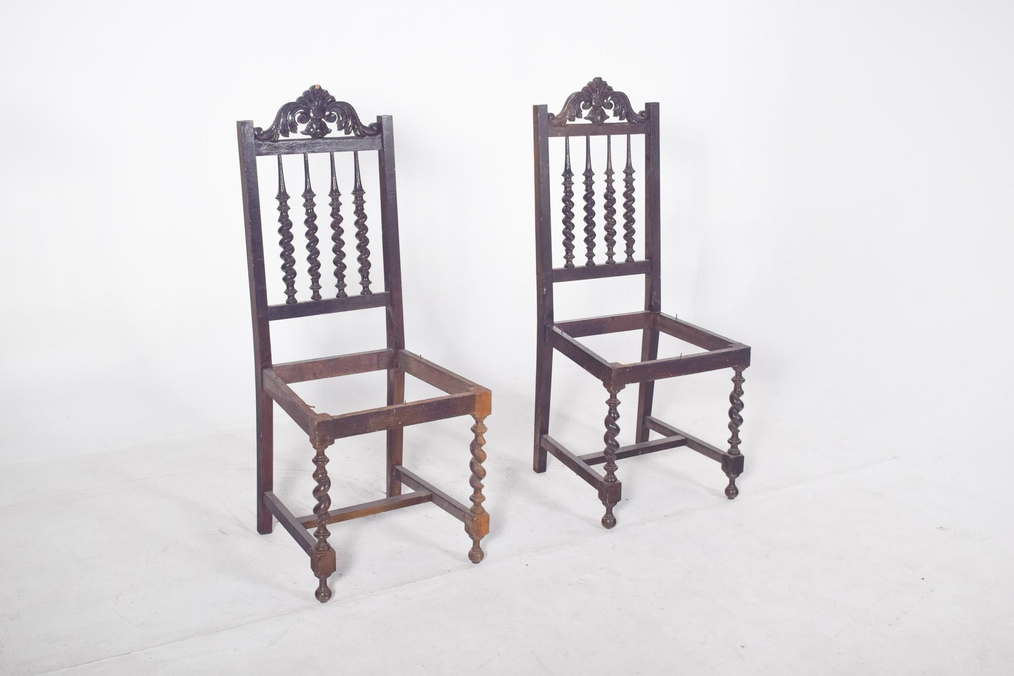 Coppia di sedie tornite. In legno scuro con schienale alto, riccamente decorato con intagli floreali sulla parte superiore e punte tornite a forma di colonne tortili, presenti anche sulle gambe anteriori. La struttura delle sedie è priva della