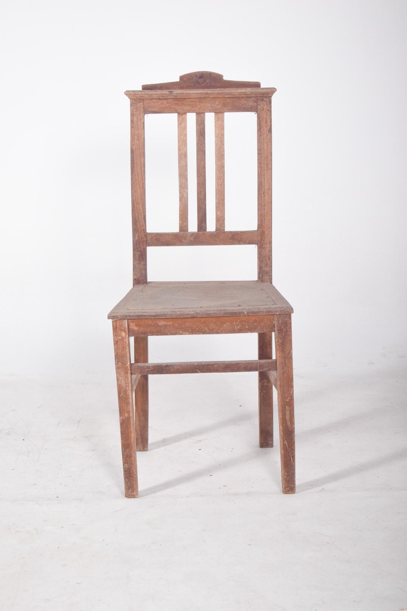 Chaise de salle à manger avec dossier géométrique. Simple et fonctionnel, entièrement en bois, avec des lignes droites et une structure solide. Le dossier comporte trois lattes verticales centrales, encadrées par un rectangle qui assure la fermeté