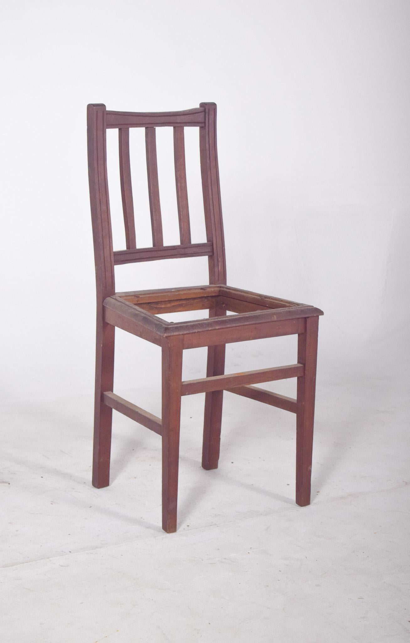 Chaise avec dossier à lattes. Cette chaise présente une esthétique simple et fonctionnelle, avec un dossier vertical composé de trois lattes centrales régulièrement espacées entre deux colonnes latérales, créant un aspect symétrique et épuré. Le