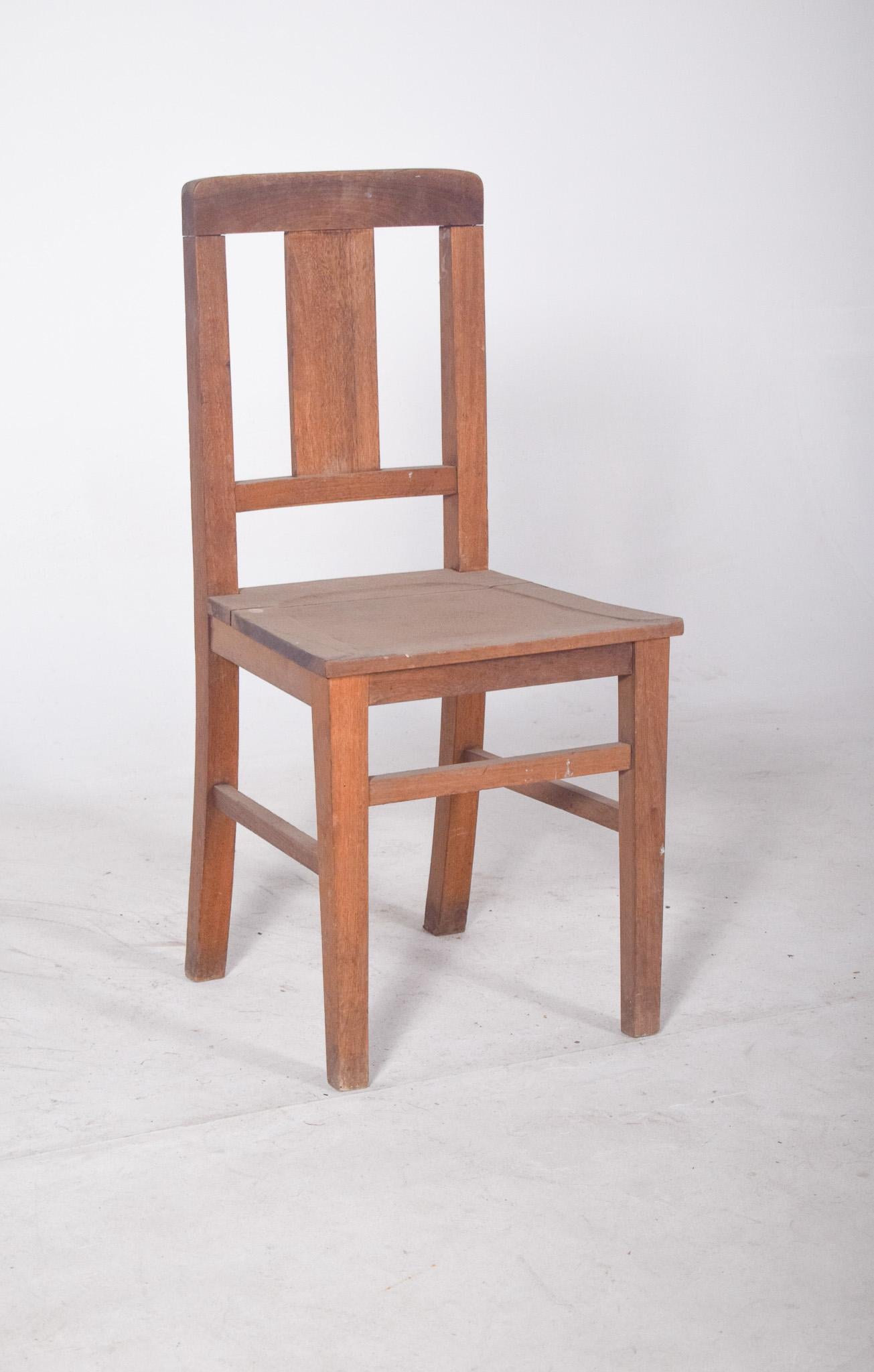 Chaise avec dossier en bois. Avec ses lignes simples et sa structure fonctionnelle, cette chaise présente un dossier droit avec une traverse supérieure légèrement arquée et une large planche verticale centrale, ce qui confère à l'ensemble force et