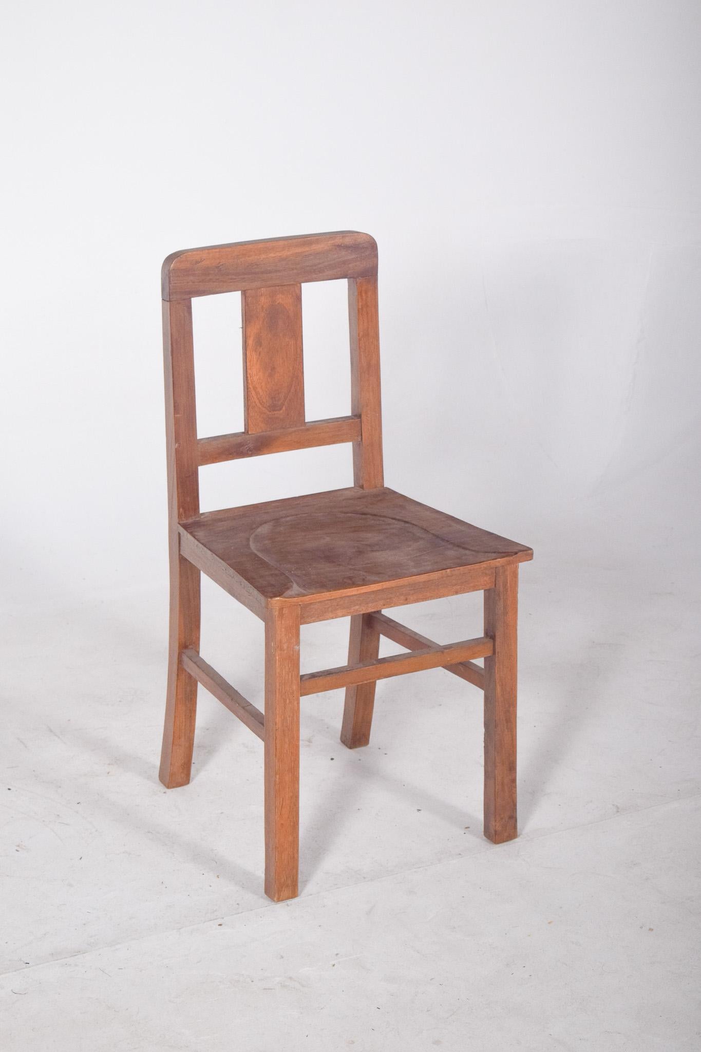 Chaise avec dossier en bois. Avec ses lignes simples et sa structure fonctionnelle, cette chaise présente un dossier droit avec une traverse supérieure légèrement arquée et une large planche verticale centrale, ce qui confère à l'ensemble force et