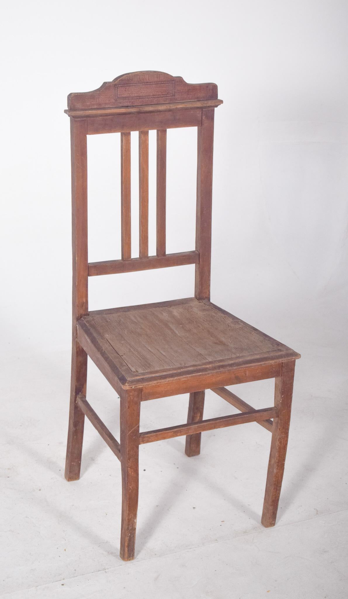 Chaise de salle à manger avec dossier géométrique. Simple et fonctionnel, entièrement en bois, avec des lignes droites et une structure solide. Le dossier comporte trois lattes verticales centrales, encadrées par un rectangle qui assure la fermeté