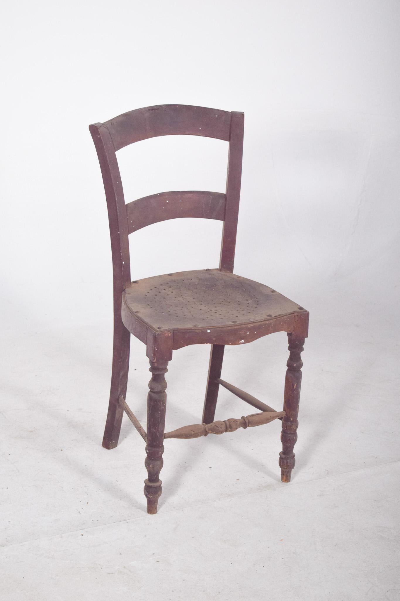 Sedia con seduta in legno traforato. Con una struttura semplice e funzionale ispirata al mondo rurale o folcloristico, lo schienale è formato da due traverse curve che assicurano ergonomia e una leggera inclinazione, mentre la base presenta gambe