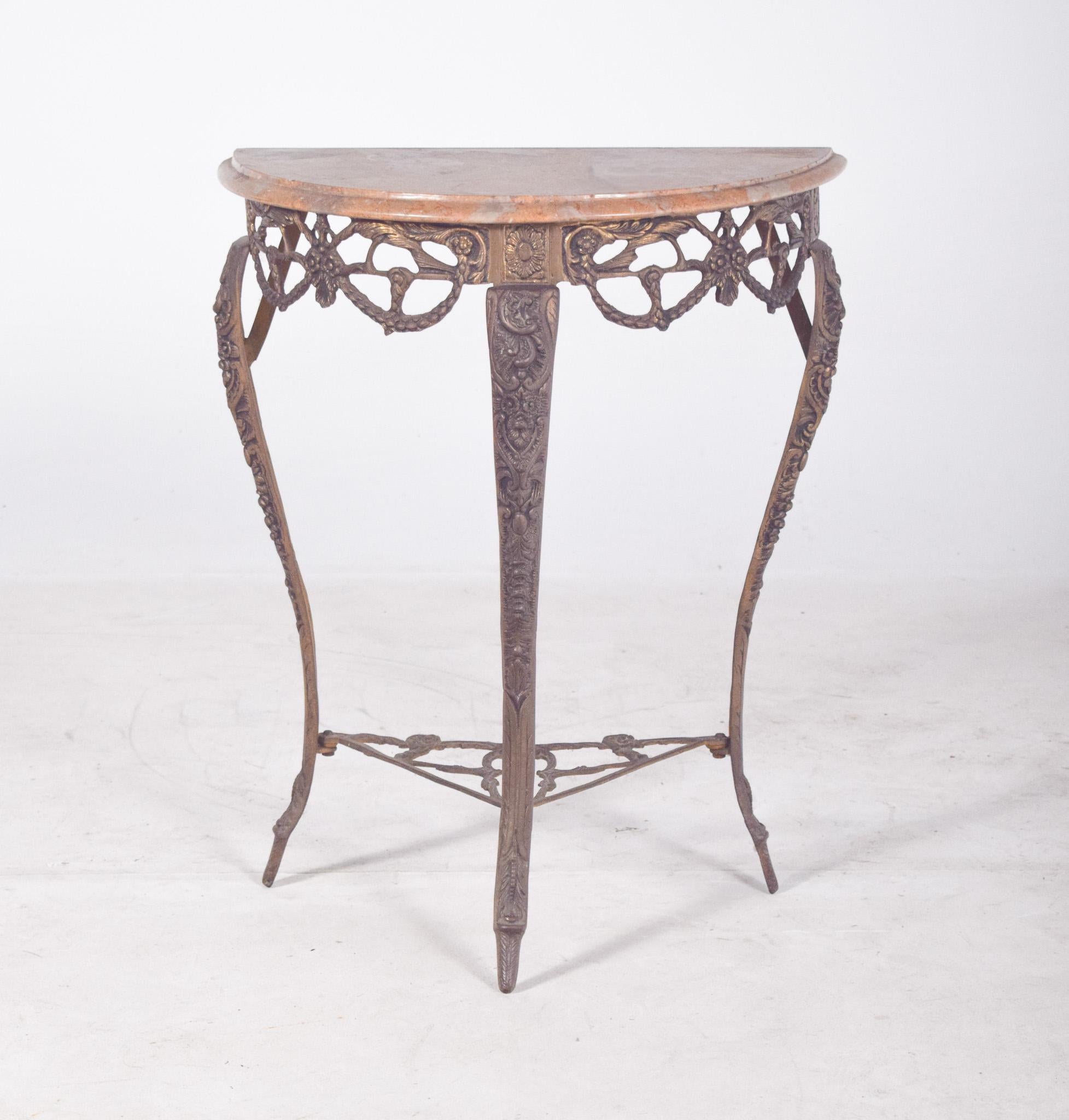 Half-moon table with marble top. With a semi-circular worked metal structure, the table has a markedly decorative style, possibly of Art Nouveau or revivalist inspiration. It stands out for the decorative details on the legs and crossbars, with