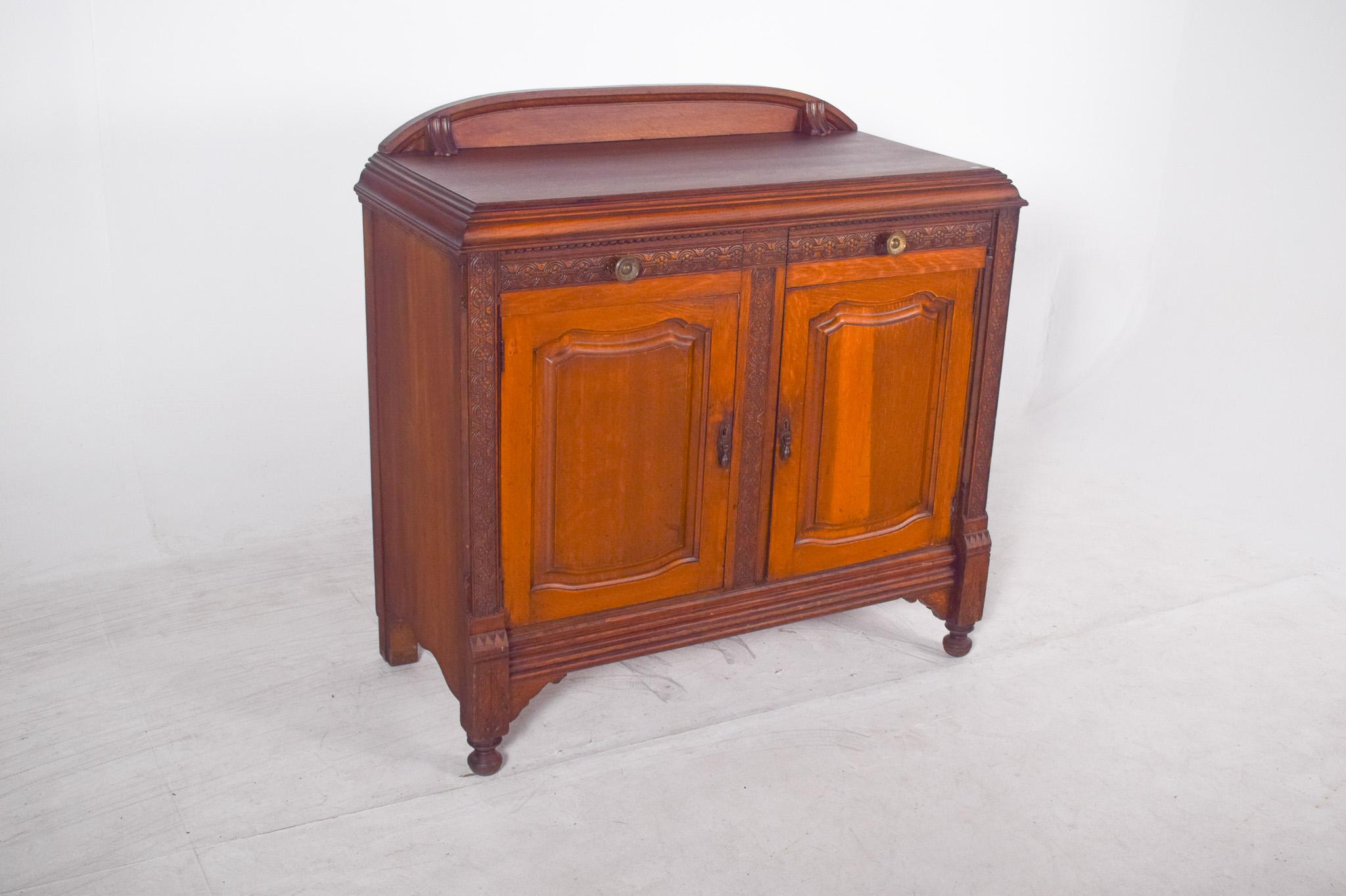 Tall sideboard in oak, with a small top. Sturdy and elegant, the small, slightly cut-out rear elevation distinguishes the piece. The structure is made up of two moulded panel doors with neo-Gothic cut-out shapes, flanked by semi-detached columns