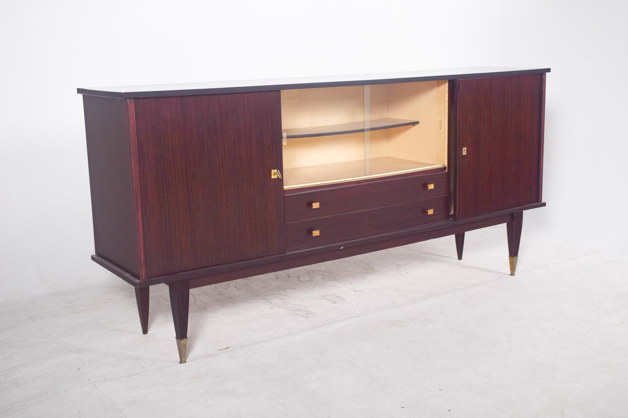 Sideboard veneered in macassar. With clean lines and an aesthetic typical of mid-20th century design, specifically the 50s and 60s, the structure is made of dark macassar wood with a polished finish that emphasises the linear texture of the wood. It