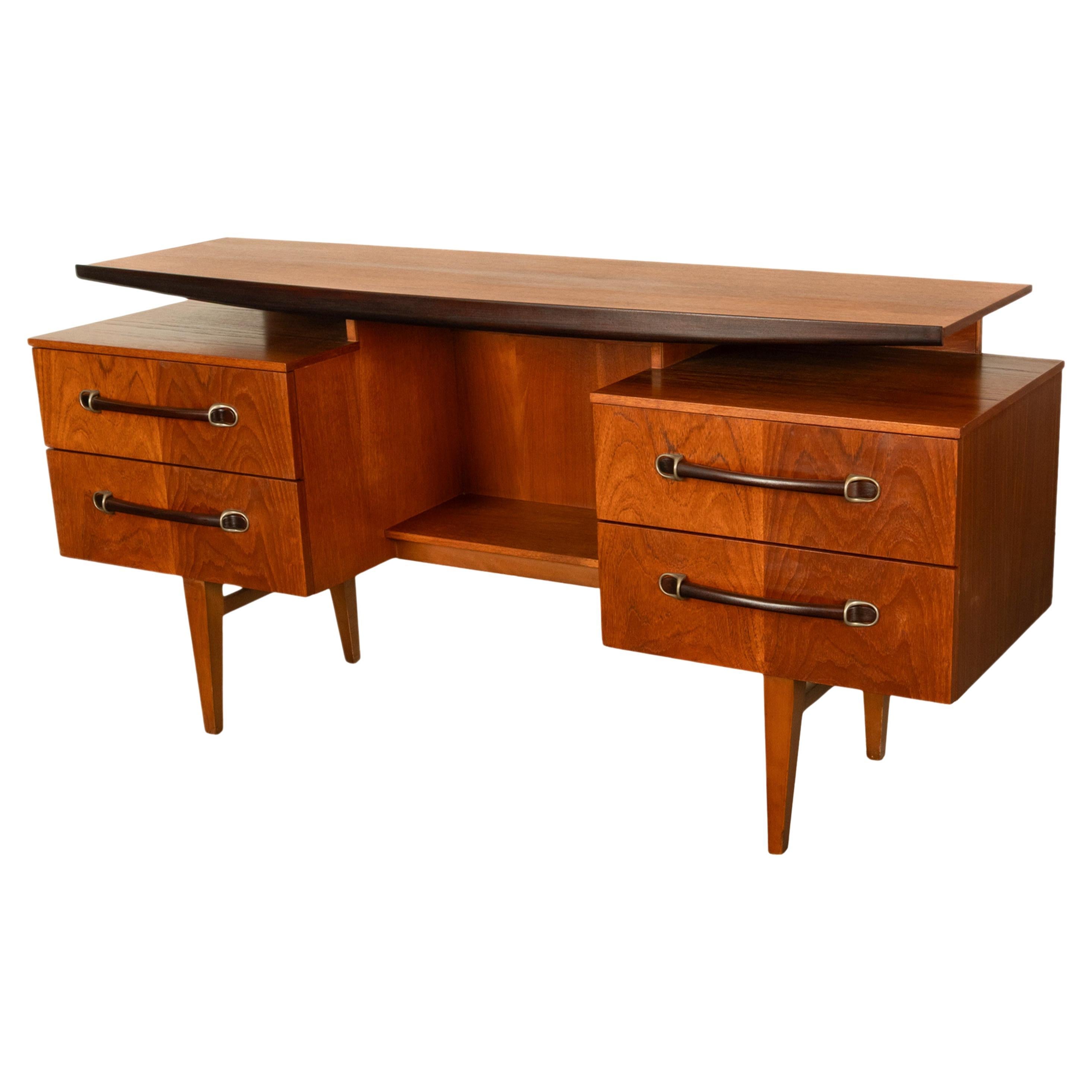 A good vintage Mid Century Modern Danish teak floating top desk in excellent condition, circa 1965.
The curved desk top with a band of rosewood to the edge floats above the desk base, which is fitted with twin drawers to each side that have