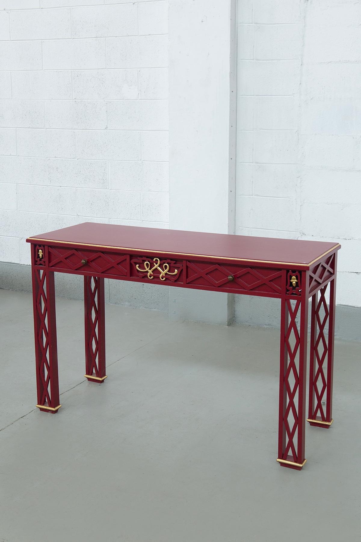 A stunning example of 1940s Italian Art Deco furniture, this elegant console table stands out for its bold design and exquisite craftsmanship. Made of wood walnut and finished in a rich red lacquer, the console features striking details that reflect