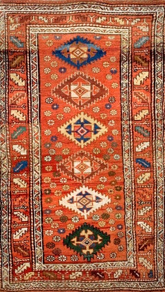 Alfombra kurda de los años 1900, pequeña, con motivos dispersos, de estilo antiguo, en tonos naranja y albaricoque, con diseño tribal y geométrico