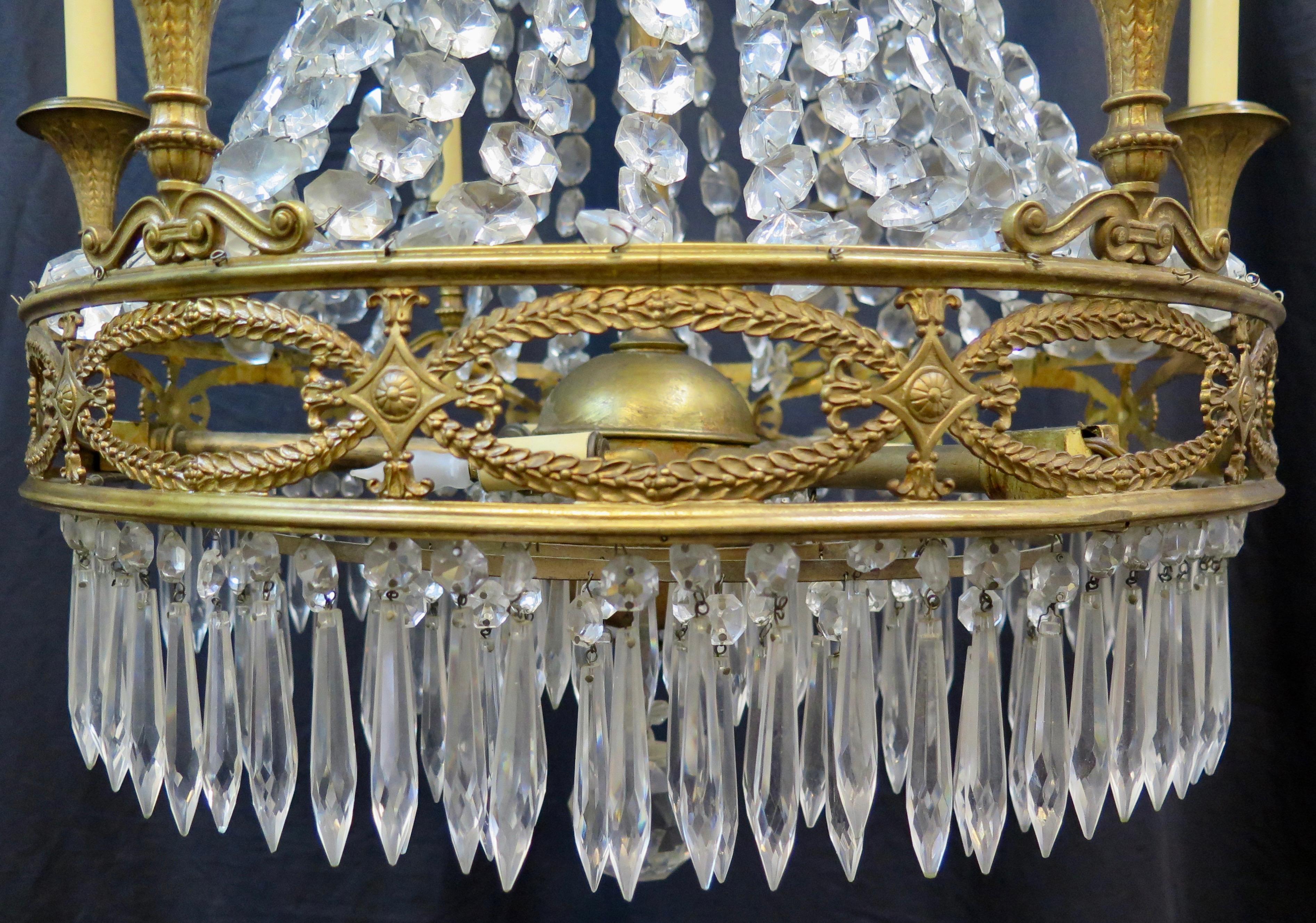 This vintage late 19th century French gilt bronze and crystal fixture is beautifully designed as an elegant formal dining chandelier. It is festooned with crystal with crystal garlands that Cascade down from a decorative bronze crown. There is an