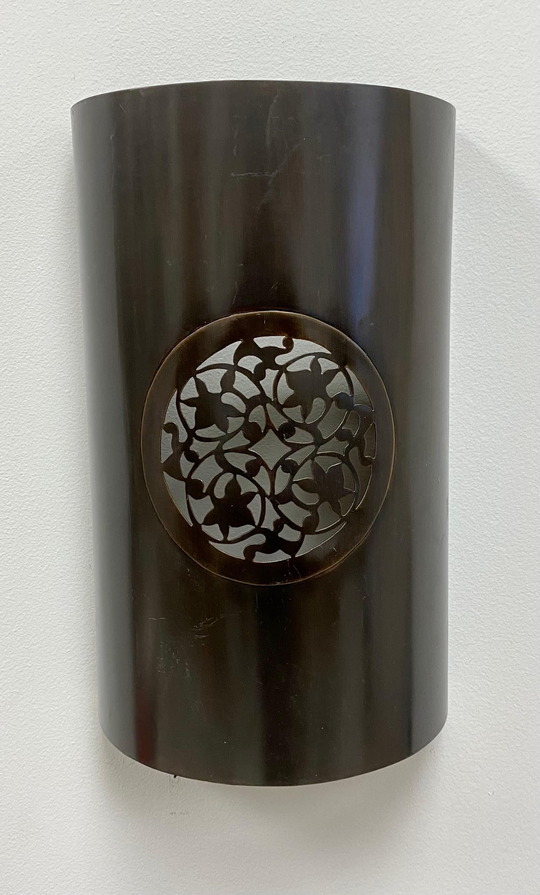 A vintage pair of handmade Moroccan wall sconces or lanterns in Pewter finish. The sconces feature a  semi-cylindrical shape and are embellished with a beautiful round leaves carved design emitting a soft and warm light for a cozy and exotic
