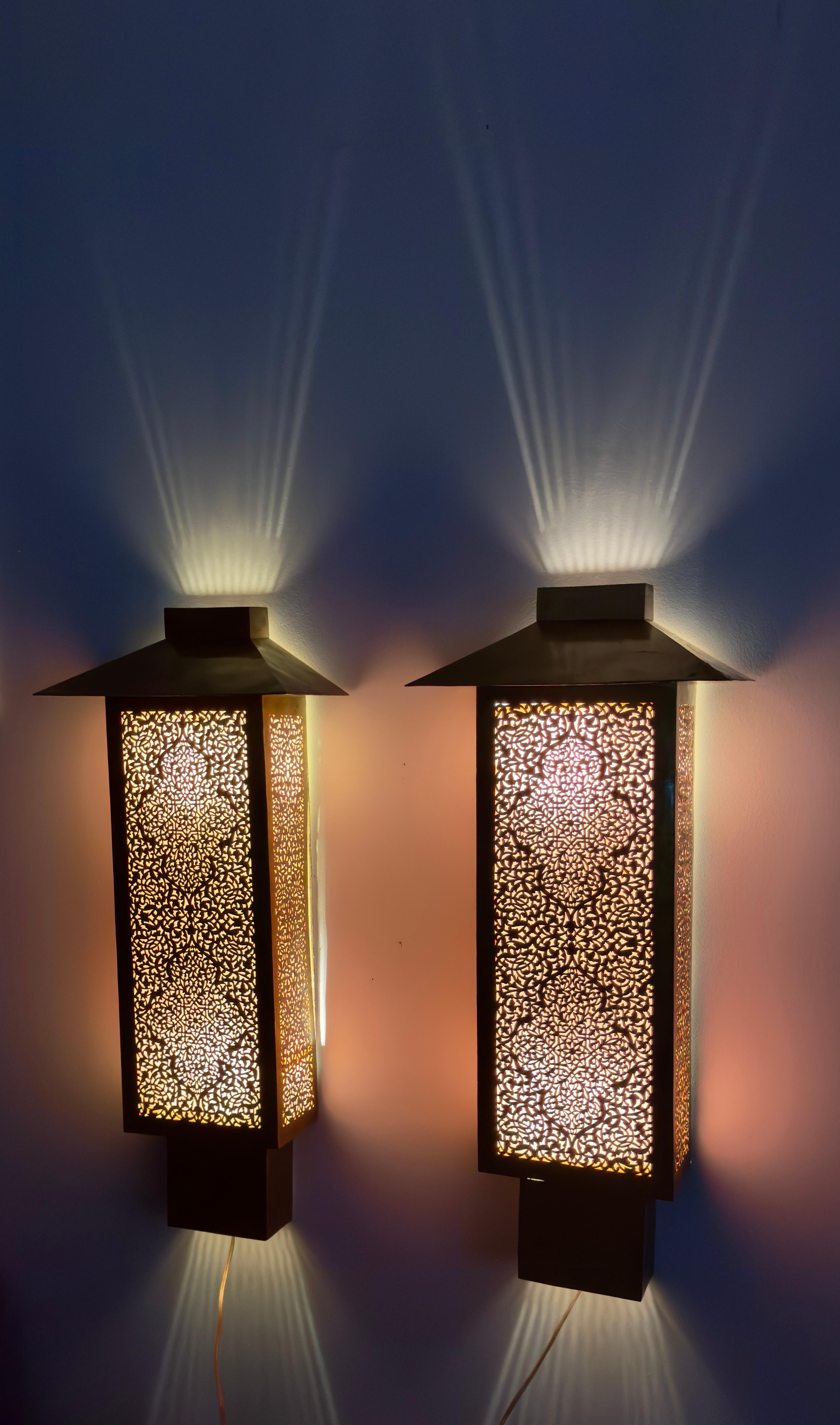 Featuring a large, sturdy base and lean, rectangular dimensions, this pair of authentically handcrafted chimney-style brass sconces will delight the senses with its exotically rendered filigree work and soft filtered light. The intricate details