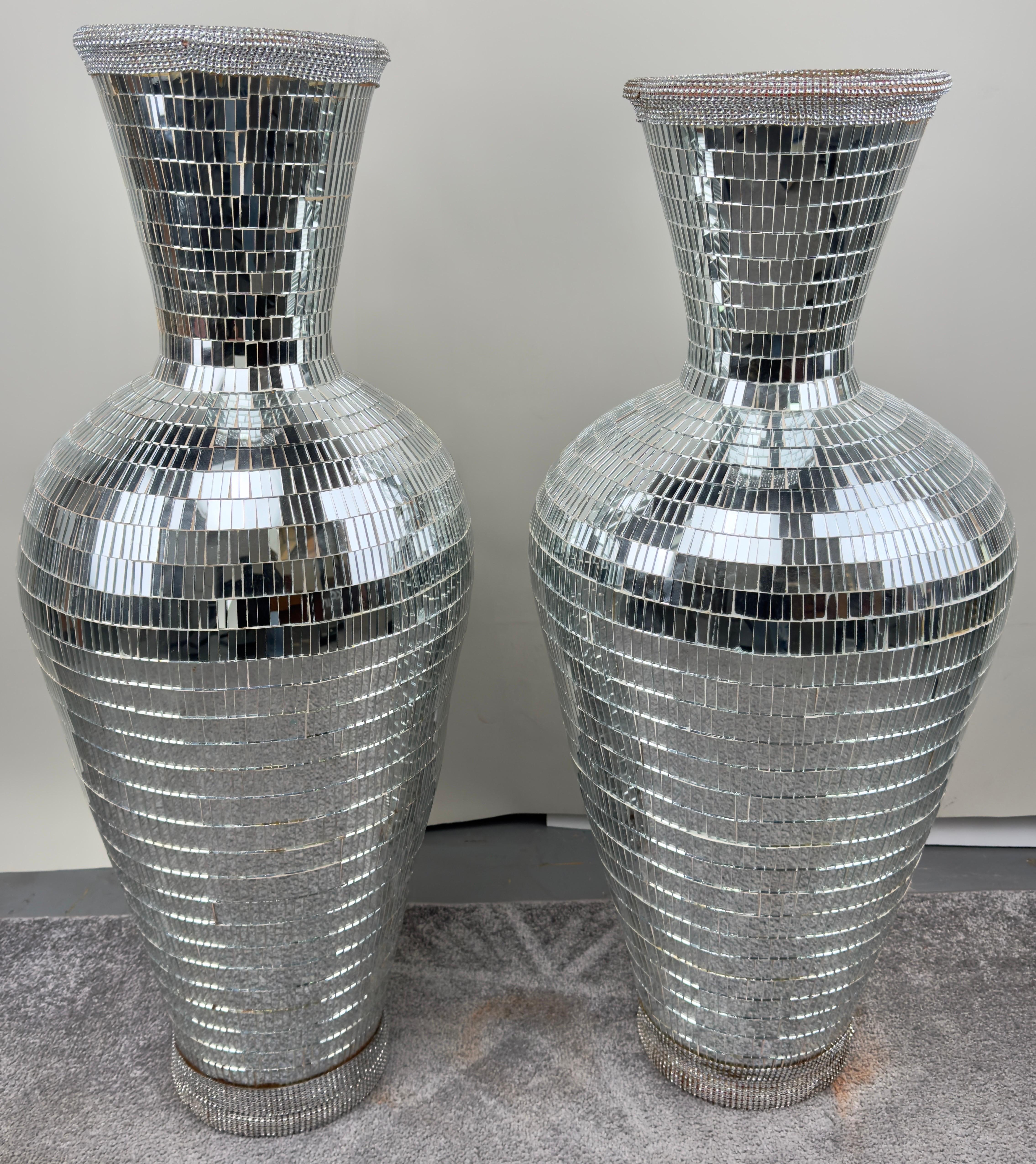 Experience grandeur with this luxurious pair of handmade Monumental Art Deco Style Micro Mosaic Mirrored Over Clay Urns. Each urn boasts intricate detailing, featuring hundreds of mirrored pieces set on a clay base. This exclusive pair exemplifies