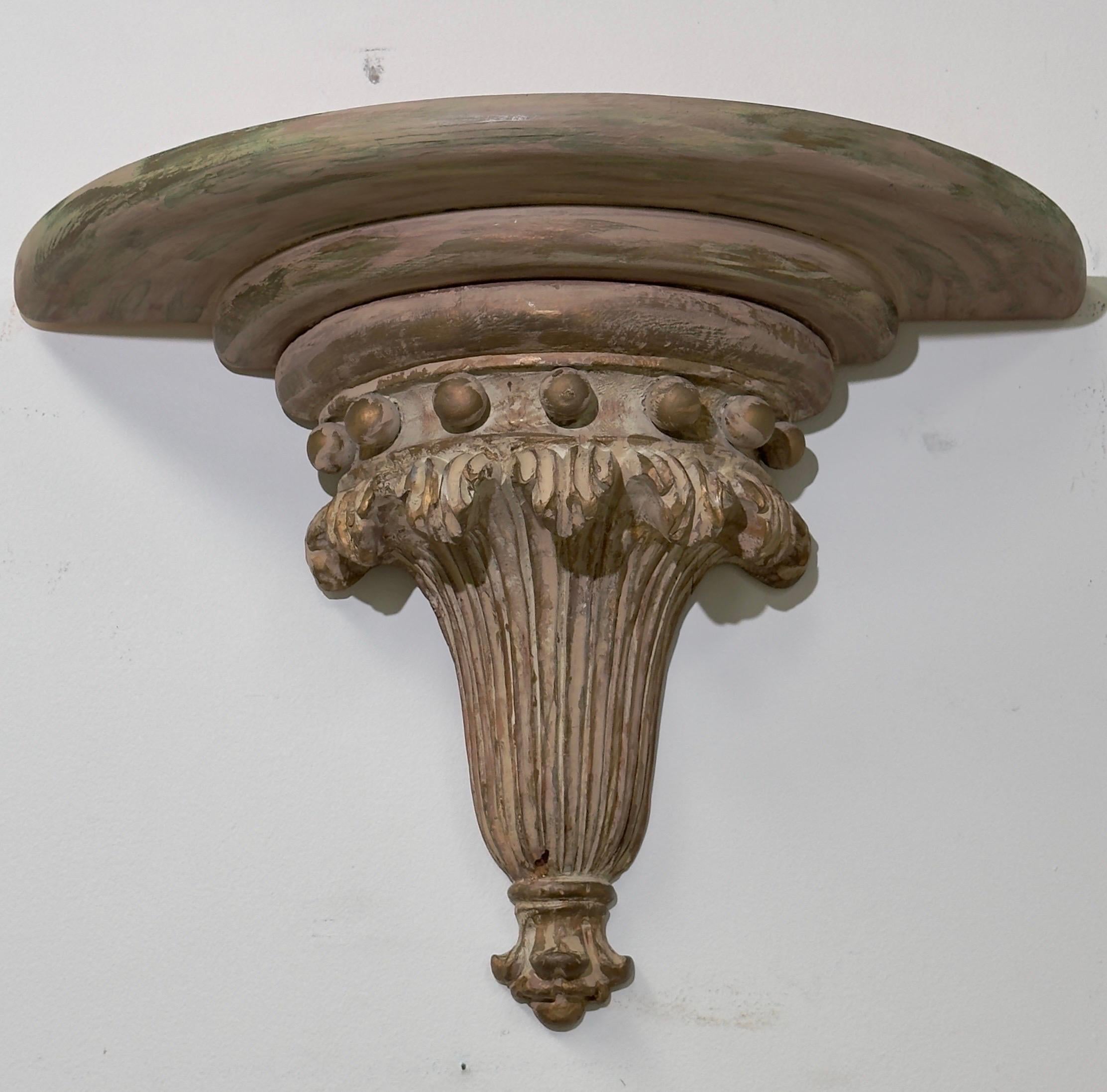 A pair of Italian neoclassical wall shelves or brackets. Crafted with meticulous attention to detail, these brackets boast intricate carvings in a graceful shell and ball design. Fashioned from wood with a charming pickled finish, they exude a