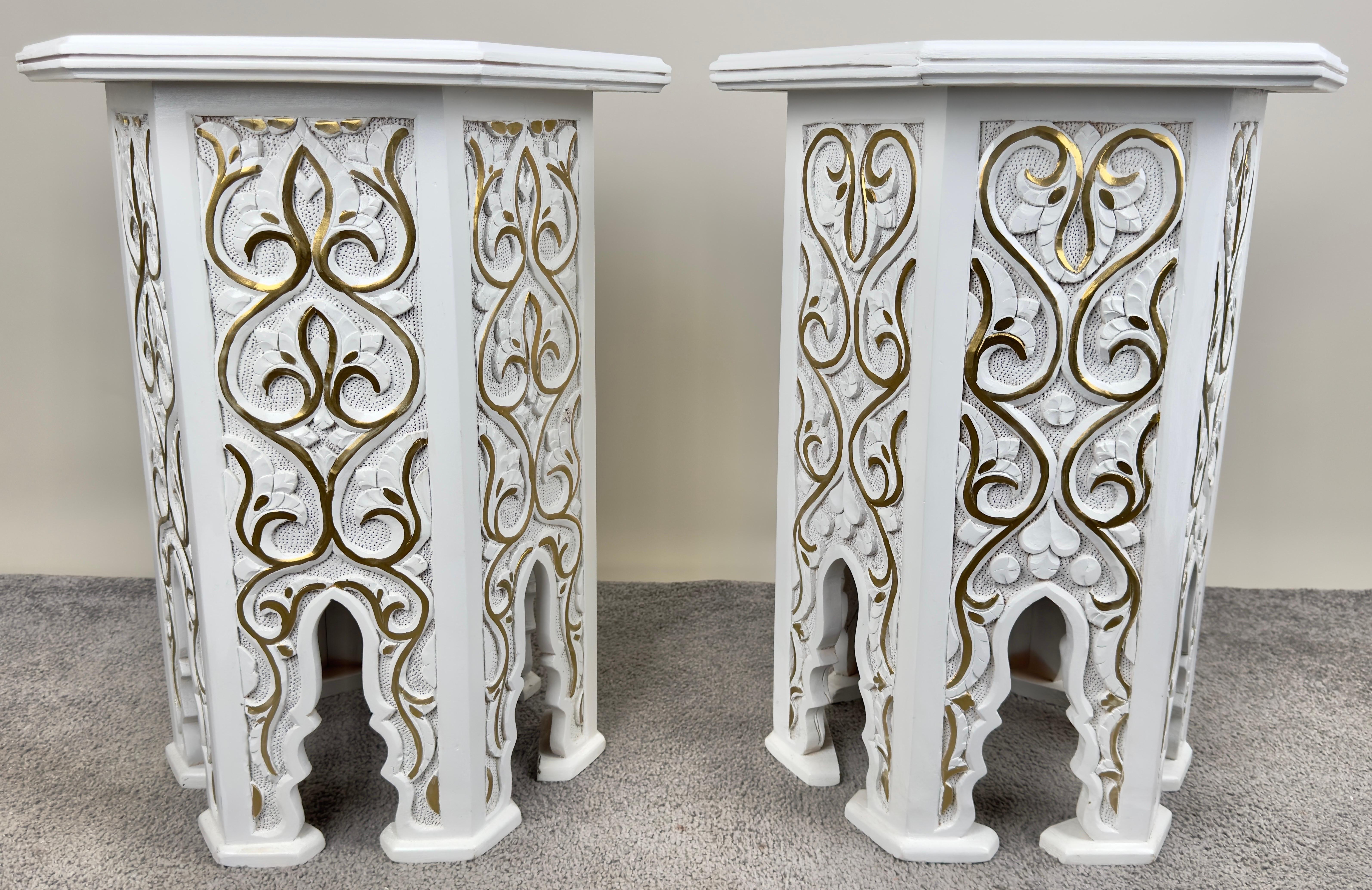 An exquisite pair of Hollywood Regency Moroccan style side or end table featuring an hexagonal shape. The handmade tables are finely painted in white and decorated in leaves Pattern painted in gold and beautiful arches, a staple of the moorish