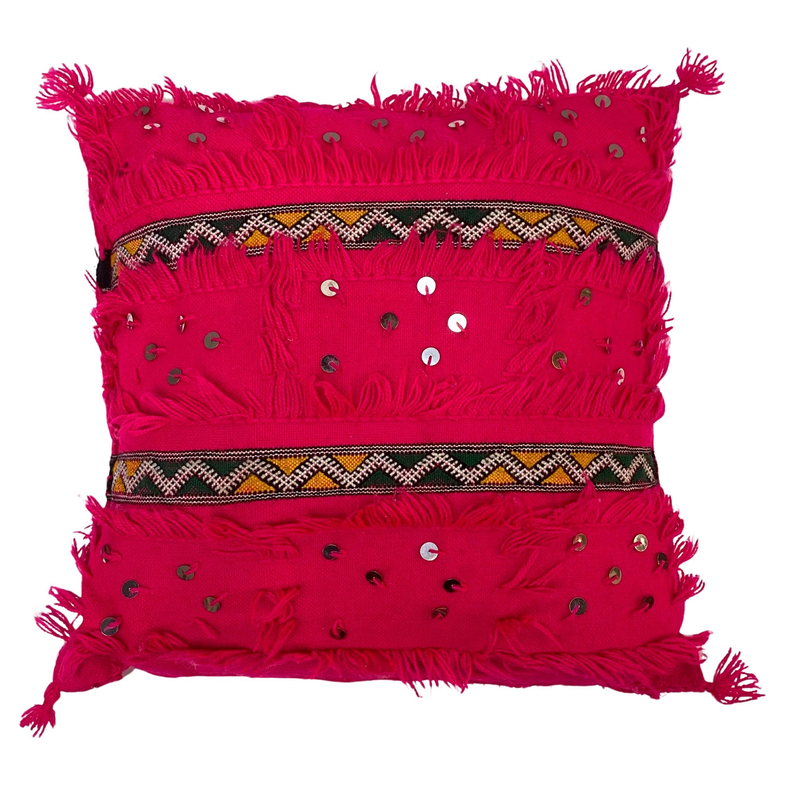 A pair of  Boho Chic Style Moroccan pink pillows.  Made of soft organic wool, the handwoven pillows feature s sequin embellishments, beautiful fringed edges, and a stunning multicolored zigzag pattern reminiscent of the berber culture of North