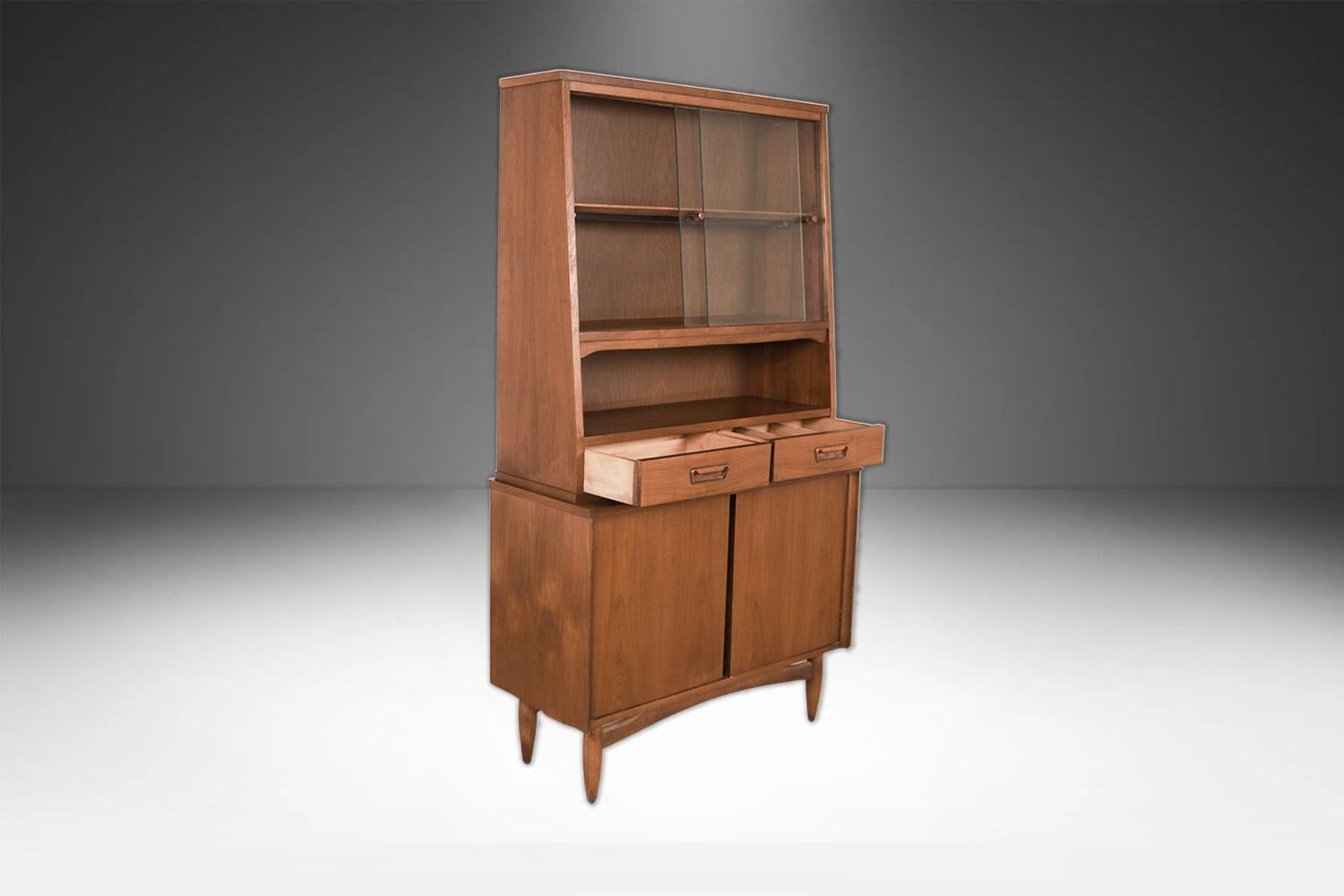 Beautiful, retro Mid-Century Modern detailed proportioned walnut buffet China cabinet in great original condition. The hutch is one solid-piece, featuring two sliding glass doors on top that open to reveal a beautiful interior that lights up with