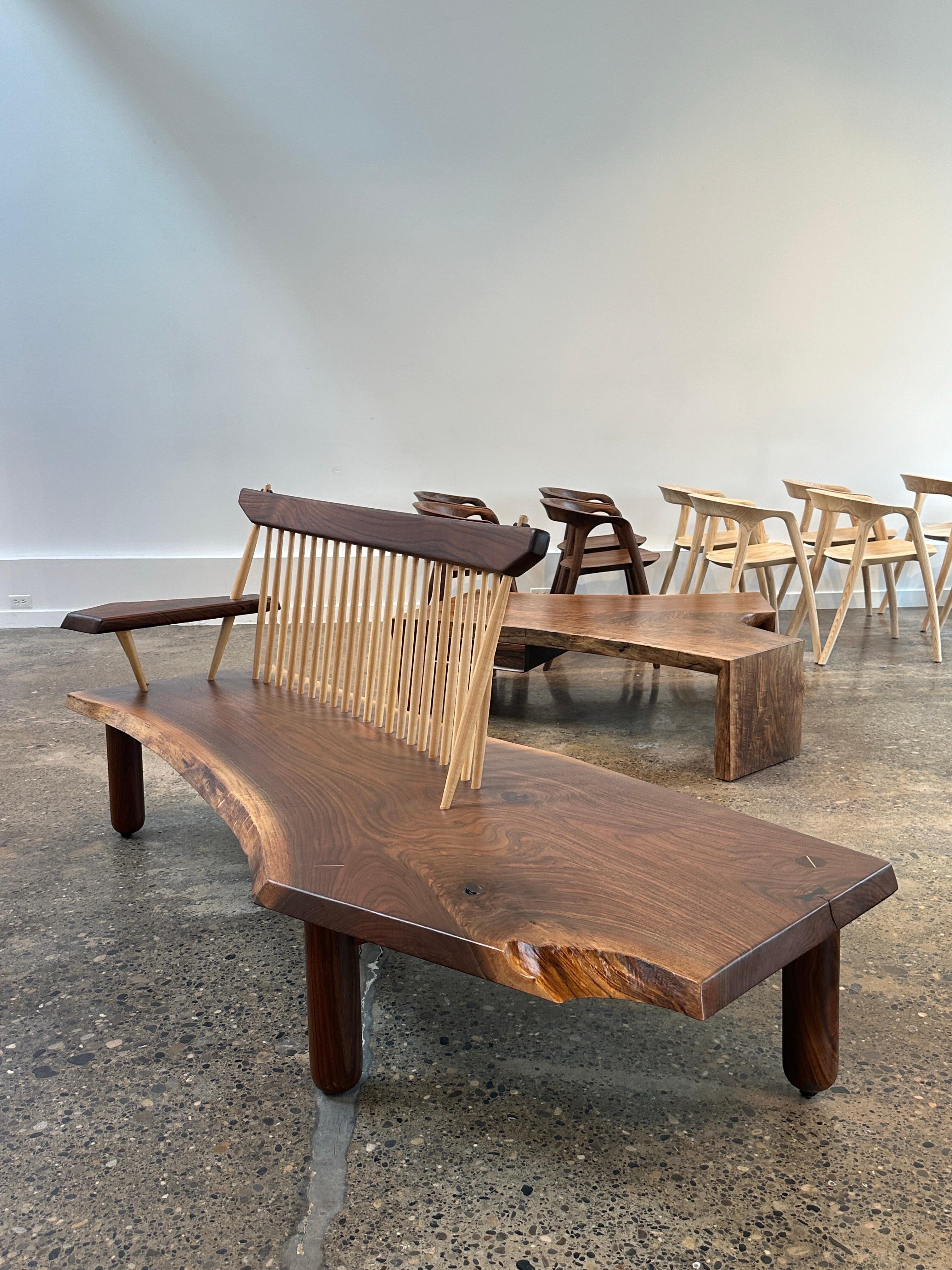 Un giro contemporáneo a un banco icónico: fabricado a mano en nogal negro americano, este banco con respaldo de huso y exageradas patas torneadas a mano es perfecto para la entrada. La carpintería se acentúa con ébano de Gabón.  Con una longitud de