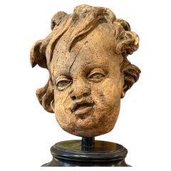 Scultura antica del XVIII secolo: testa di putto intagliata in legno di tiglio su piedistallo