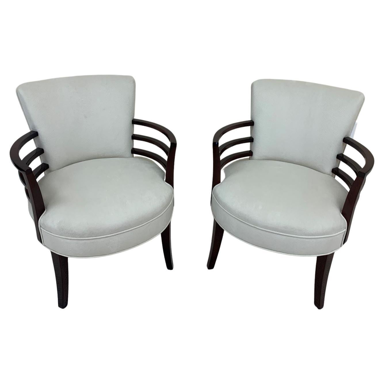 Pair of Art Deco circular chairs in the style of Gilbert Rohde. Unique design with the three speed band arms following the curve of the seat. Beautifully restored wood in a walnut gloss finished, complimented by a faux pony skin upholstery.