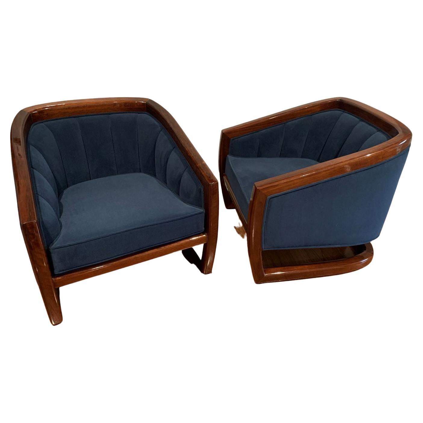 Beautifully restored pair of mid century tub chairs in the style of Milo Baughman. Solid rosewood trim with a deep royal/navy blue cotton upholstery. The upholstery is tailored and classic with a stunning channel back. Dimensions 27 inches wide 29