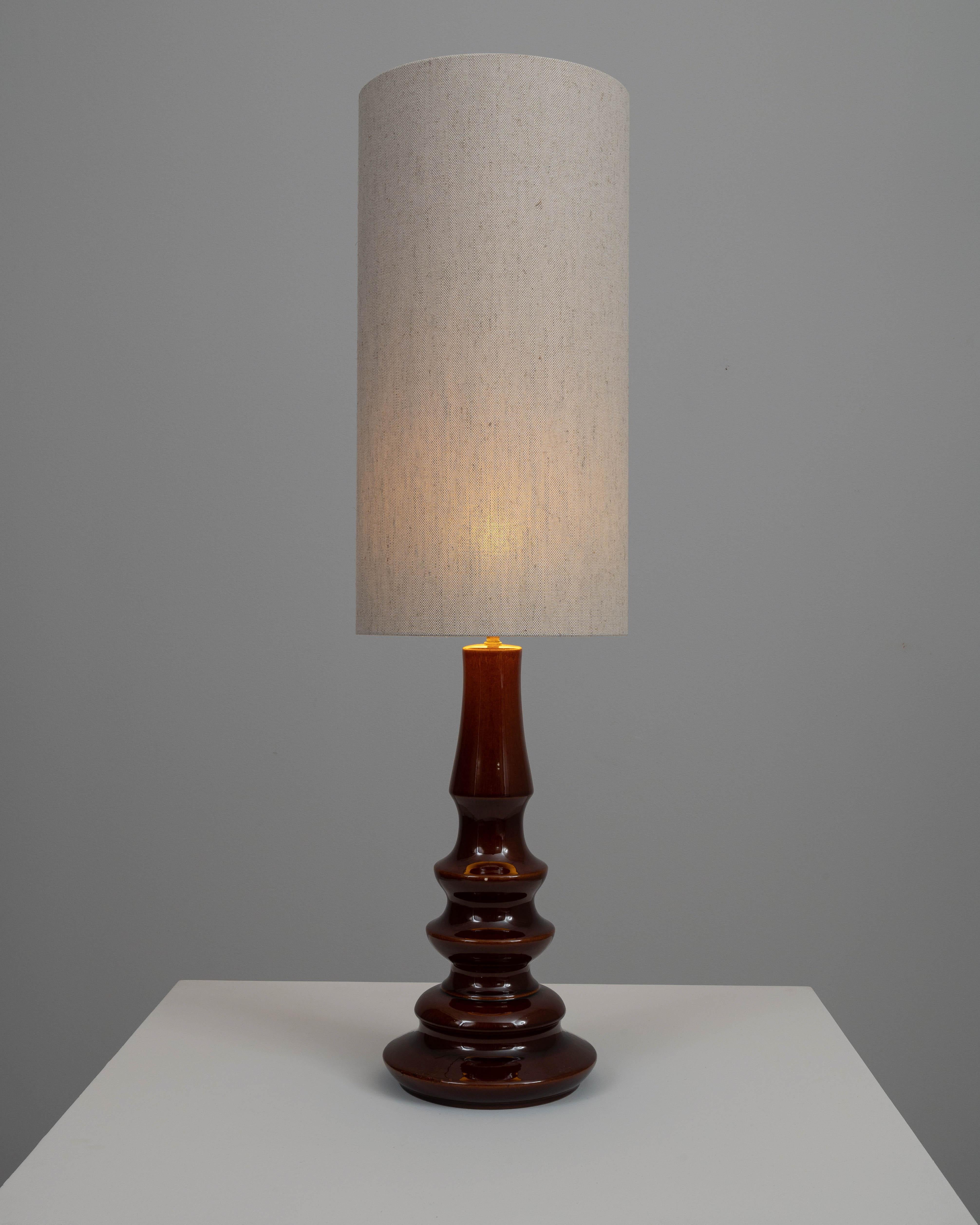 Elevate your interior decor with this early 20th-century British ceramic table lamp. This exquisite piece features a richly glazed brown base with a unique, sculptural silhouette that adds a touch of sophistication to any room. The lamp is topped