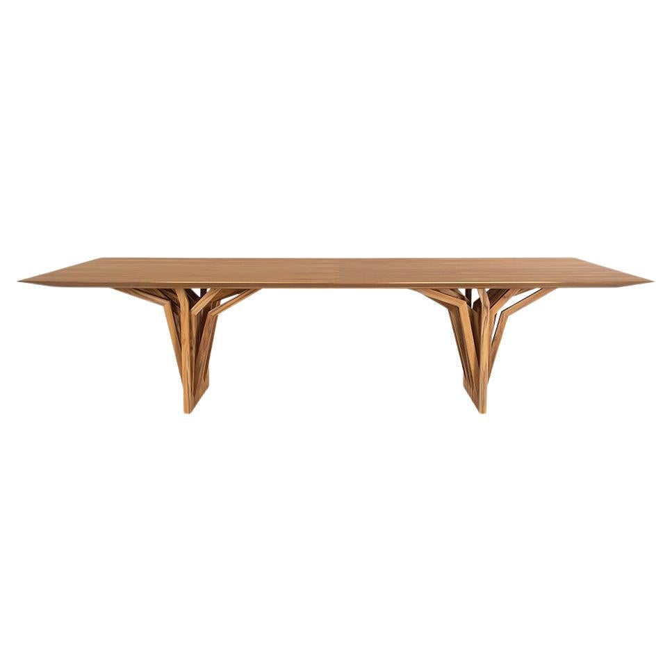 La table de salle à manger Radi est un chef-d'œuvre avec un plateau en placage de bois finition teck et une base de table originale en forme d'ancre de toiture, inspirée par les racines aériennes des arbres. Cette table de salle à manger est une