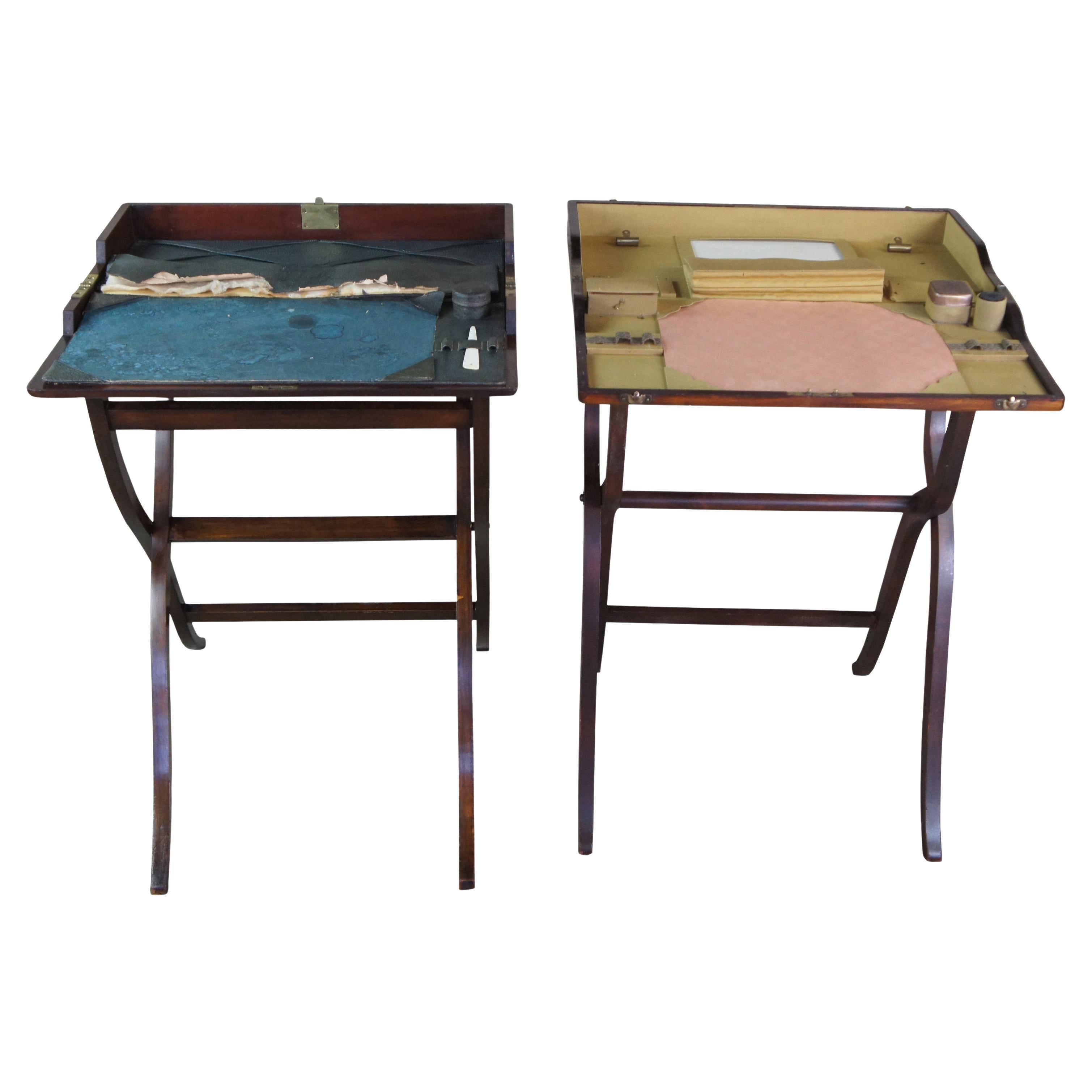 2 Escritorios de campaña británicos de la época de la Guerra Civil.  De caoba, con una forma plegable que se abre a una superficie de escritura con tinteros y espacio para guardar cartas.  Formas e interiores ligeramente distintos, uno de ellos con