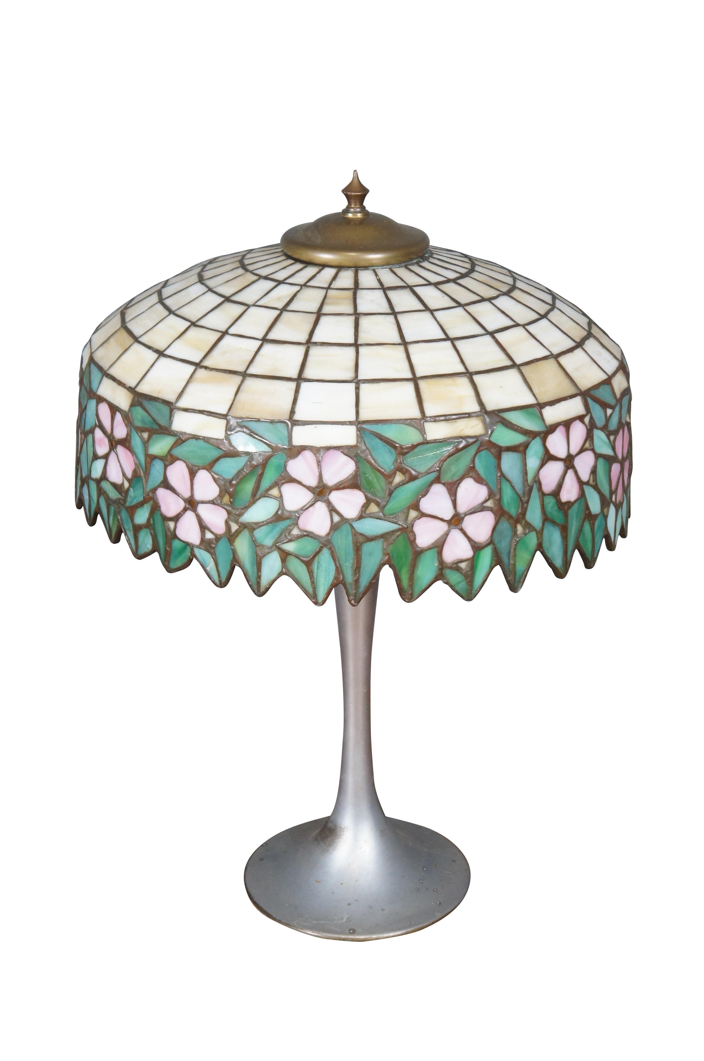 Lampe de table ancienne du milieu ou du début du 20e siècle, à deux lumières, à base d'aluminium, avec un abat-jour en vitrail de style Whiting présentant un treillis blanc cassé garni de feuilles tombantes et de fleurs roses. 

Dimensions :
7.25