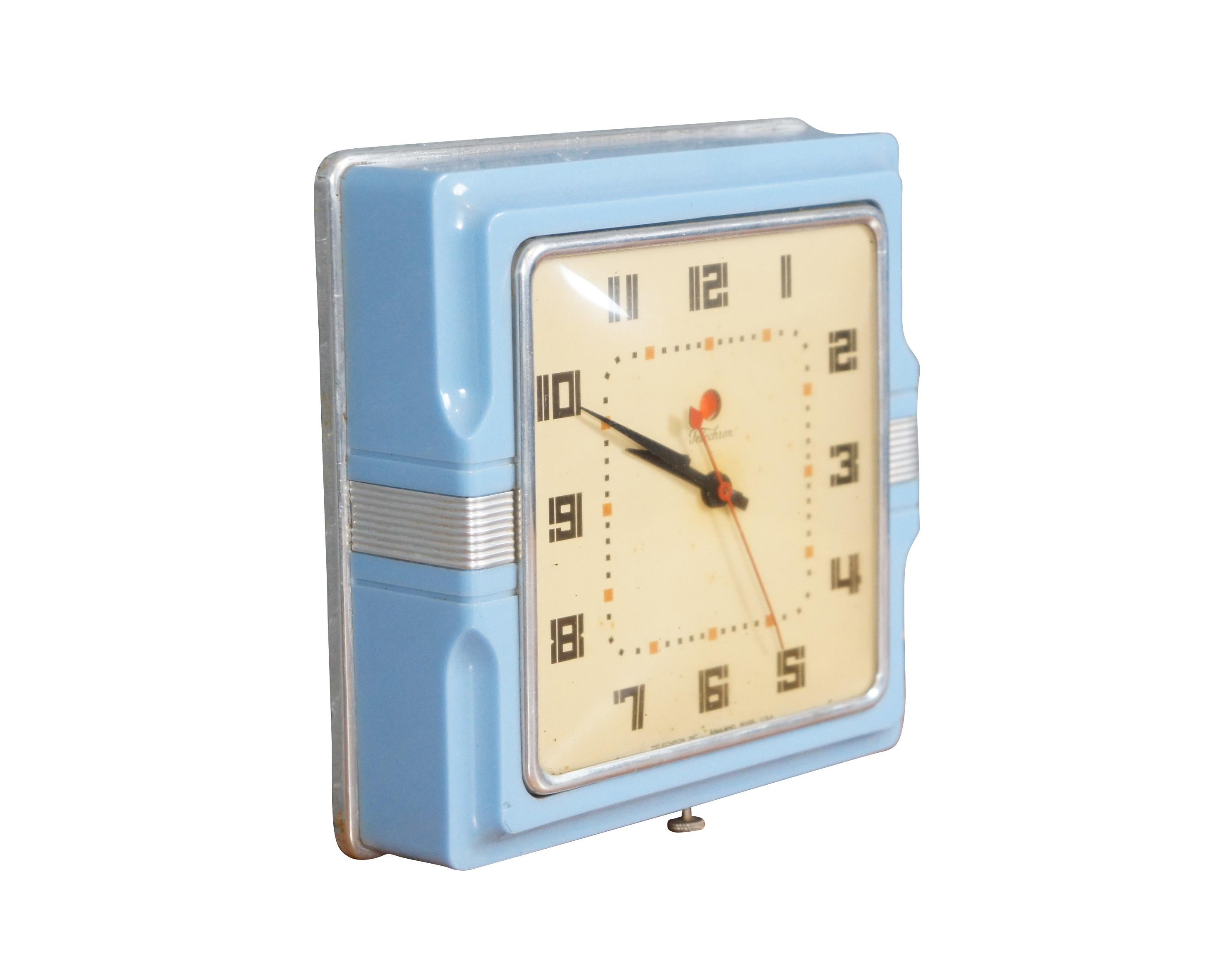 Vintage mid 20th century Telechron electric wall clock, Model 2H11, featuring the rare baby blue Bakelite case with silver accents and art deco styling. Yellowed face with black stylized art deco Arabic numerals and hands; black and orange minute