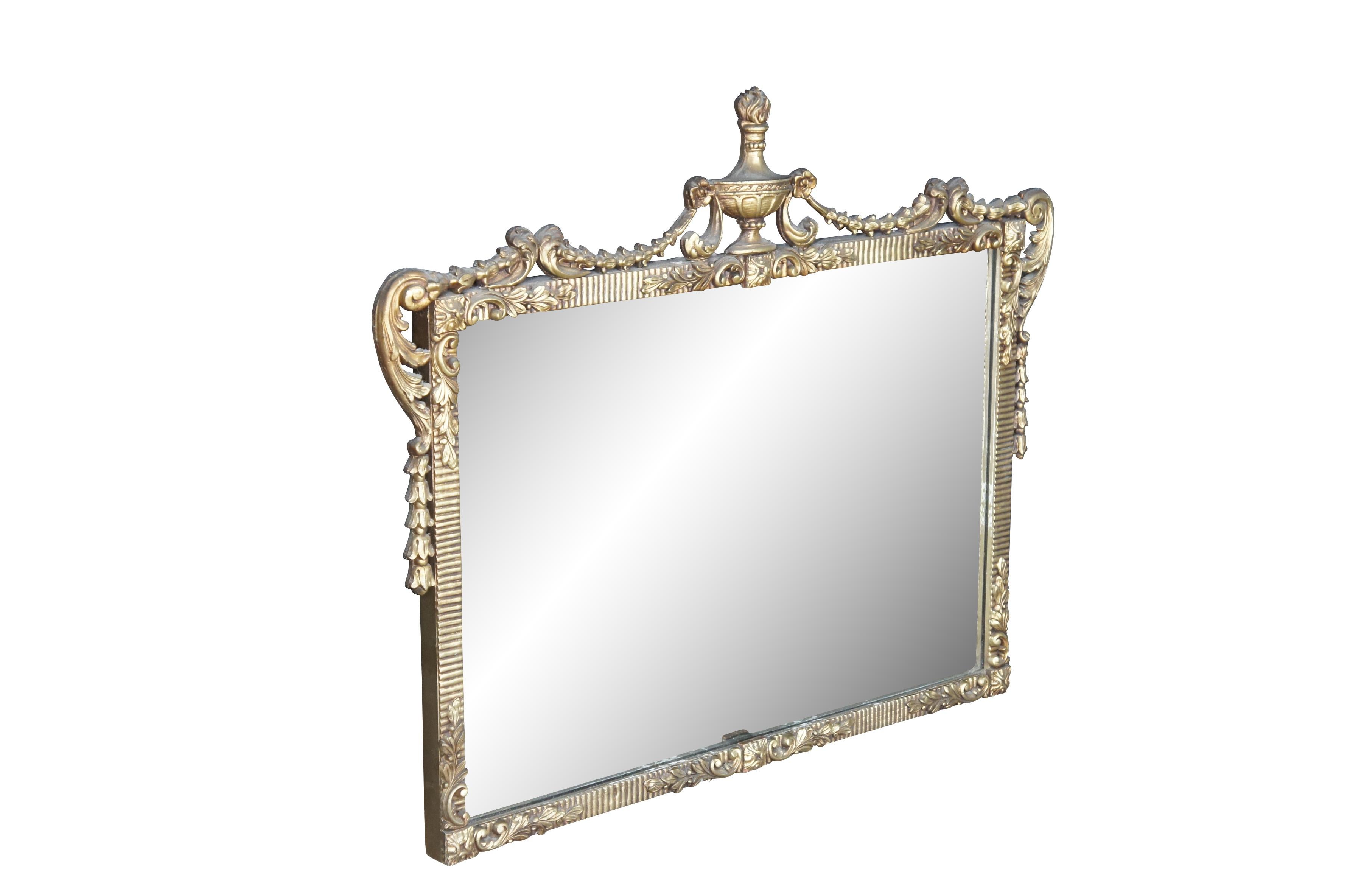 Un affascinante specchio di ispirazione neoclassica francese dei primi del Novecento.  Presenta una corona a forma di urna greca con volute neoclassiche e dettagli fogliacei. La cornice rettangolare presenta medaglioni francesi, dettagli fogliacei,