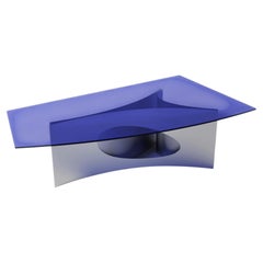 Tavolo da pranzo moderno di Atelier Ferraro, con base curva in alluminio e piano in vetro blu