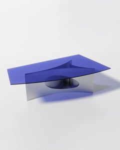 Tavolo da pranzo moderno di Atelier Ferraro, con base curva in alluminio e piano in vetro blu