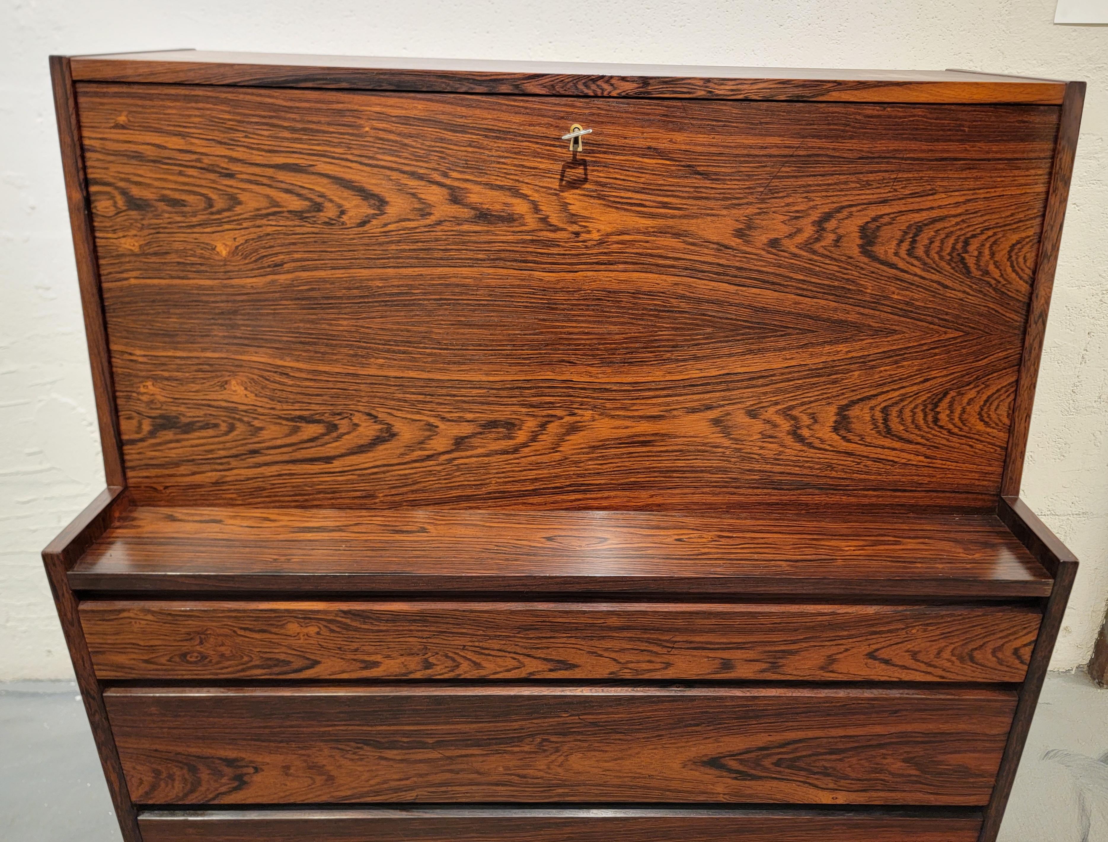 Una scrivania moderna danese con 3 cassetti e piano di scrittura. Bellissima venatura di palissandro con una patina ricca e profonda. La scrivania conserva la sua finitura originale ed è in eccellenti condizioni vintage. I cassetti scorrono senza