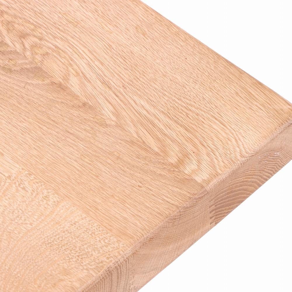 A substantial table featuring a thick solid oak slab top with beautifully exposed grain and natural variation. The top rests on a traditional trestle base with robust supports and pegged joinery, emphasizing the honesty of construction and enduring