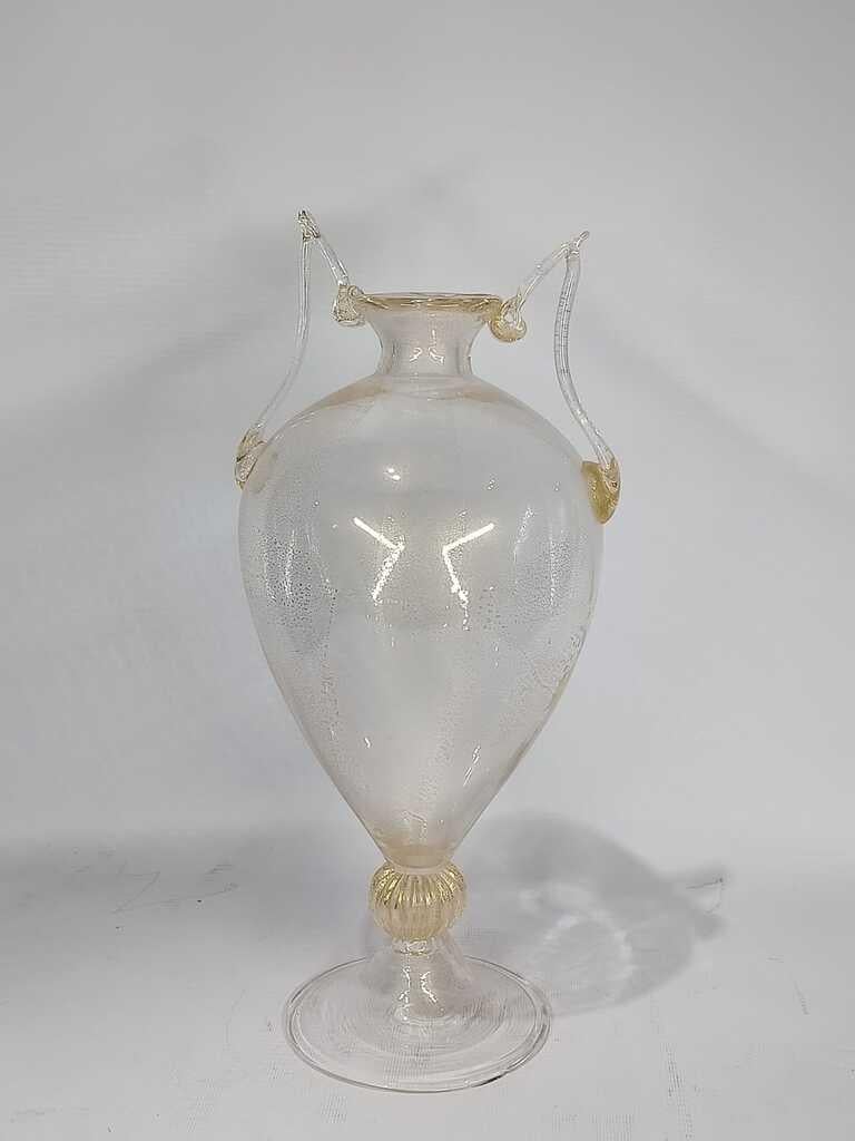 Vetro di Murano
Vaso con due maniglie
Origine - Italia
Metà secolo
Circa 1950.

Firma di iscrizione (illeggibile)
sulla base.
Condizioni eccellenti. È presente solo una scheggiatura (molto piccola) sul bordo della base (facile da lucidare).
Tecnica