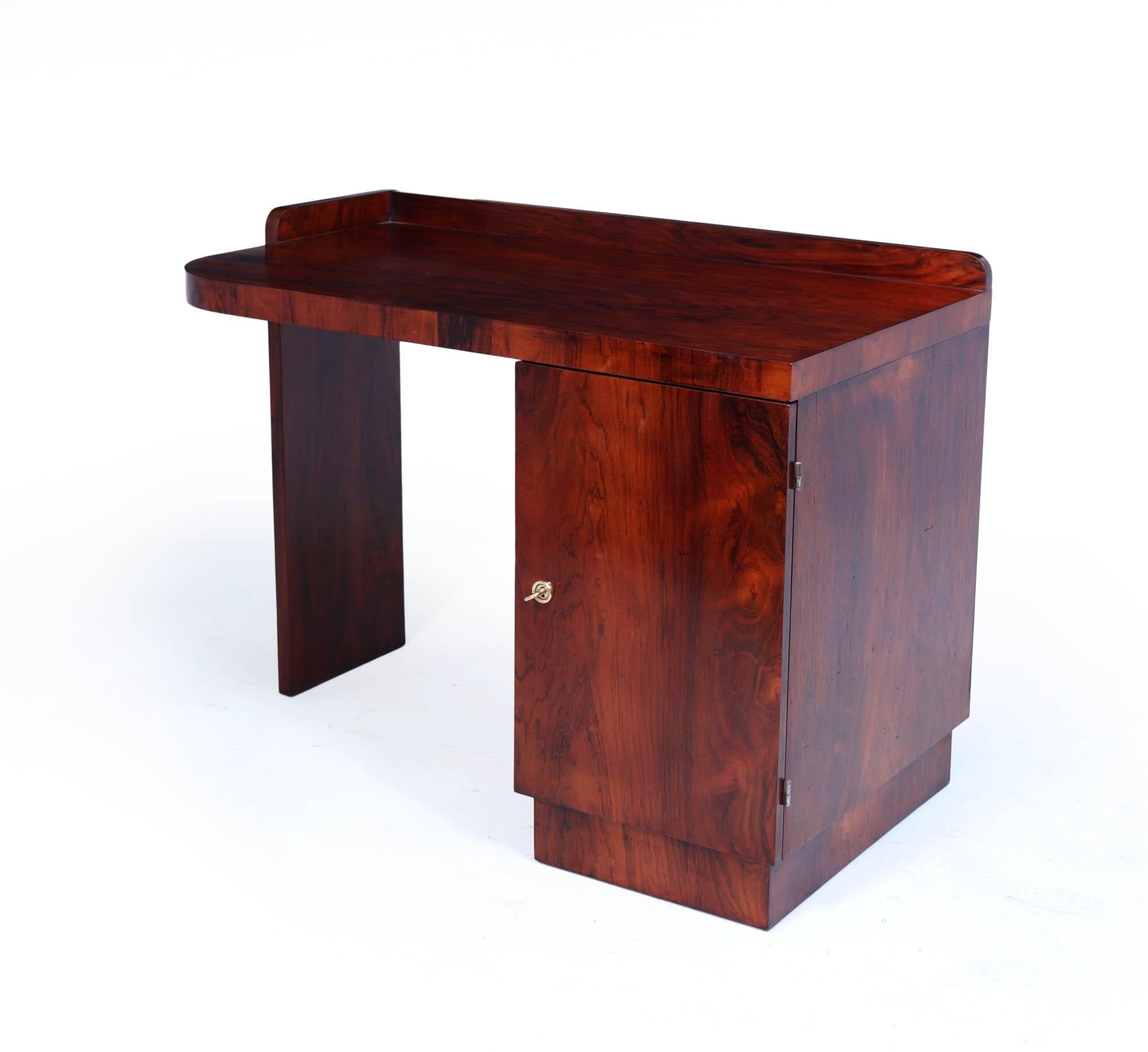 Dieser auffällige Original-Schreibtisch aus der Zeit um 1930 ist ein hervorragendes Beispiel für das stromlinienförmige Design und die luxuriösen Materialien, die diese Epoche prägten. Aus reich gemasertem Palisanderholz gefertigt, strahlt er Wärme